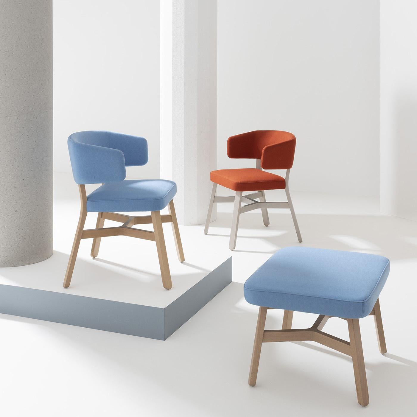 As inviting as an embrace, exclusive as an haute-couture, colorful dress. This chair by Emilio Nanni - characterized by the crossing of wooden elements under the seat distinctive of the Croissant Collection - flaunts a silhouette fashioned of