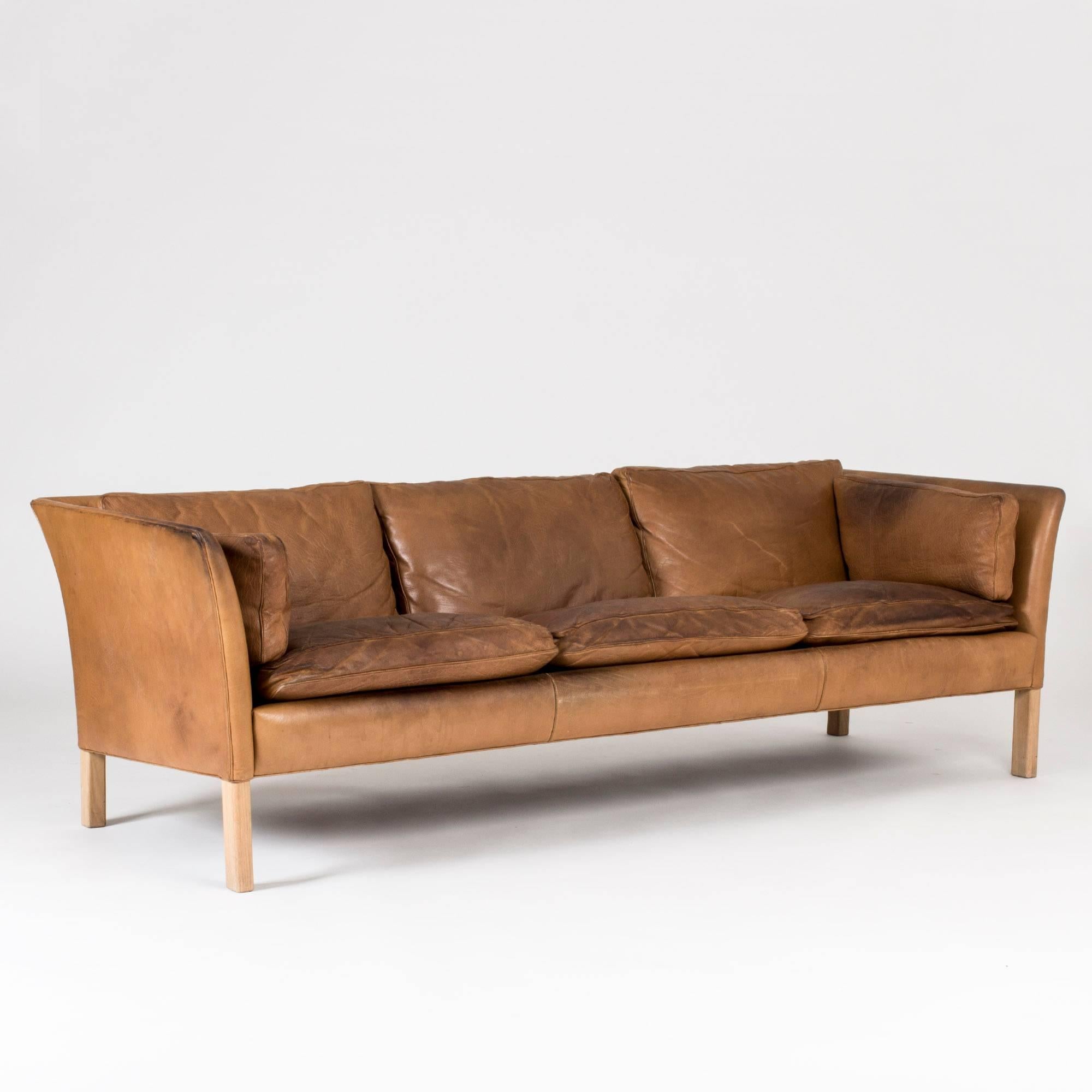 “Cromwell” three-seat sofa in cognac colored leather by Arne Norell. Timeless design with a lightness and elegantly curved armrests.