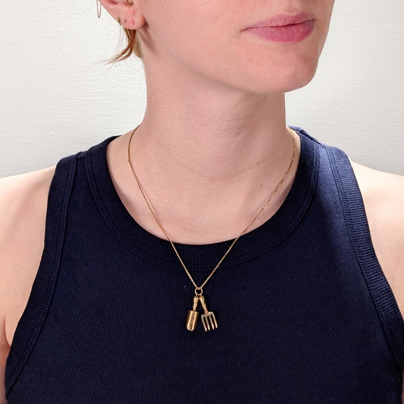 A fine, signed English gold charm.

In 9 ct yellow gold.

By Cropp & Farr of London in 1994. 

In the form of a gardening trowel (or hand shovel) and gardening fork. 

Each with integral bails and sharing a jump ring.

Doubles nicely as a