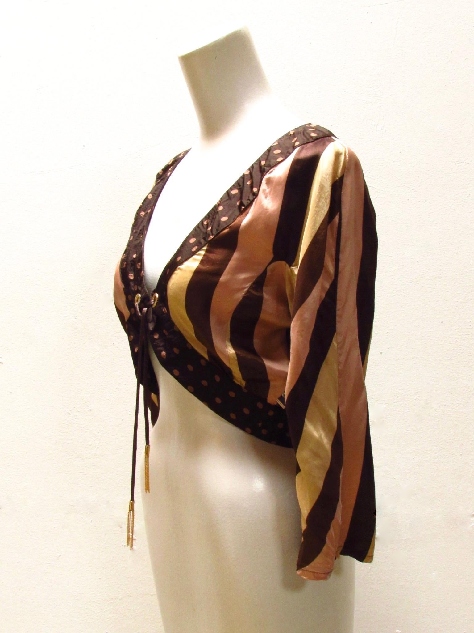 This darling silky soft shrug-style jacket from vintage Jean Paul Gaultier is a chocolate brown color with pink polka dot edging and a striped bodice. The front is secured with a delicate self-fabric tie finished with dangling brass chain, fed