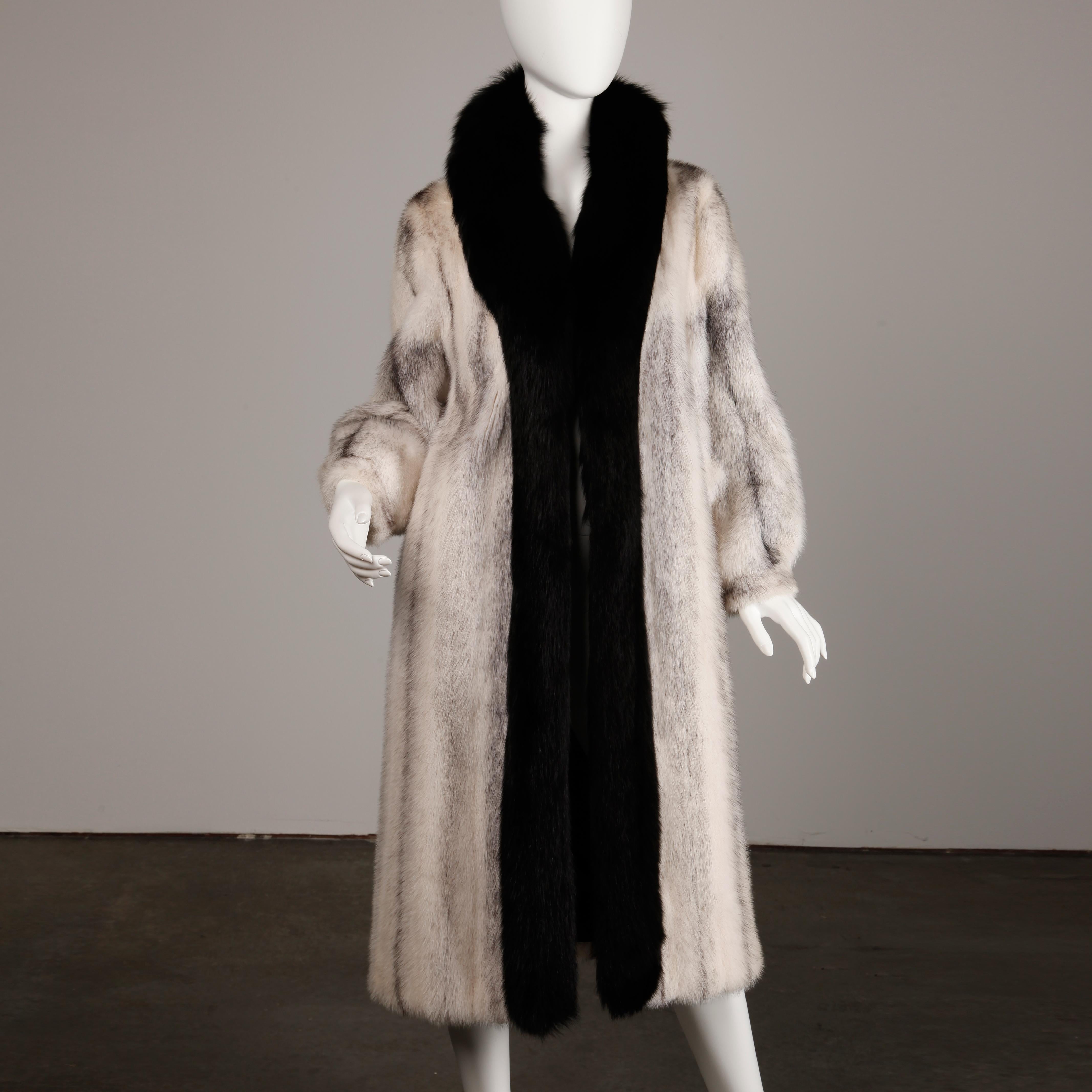 Stunning black and white cross mink fur coat with plush black fox fur collar and front edges. Flattering cut with fuller sleeves and beautifully matched pelts. Front hook closure. Fully lined in black with a monogram of 