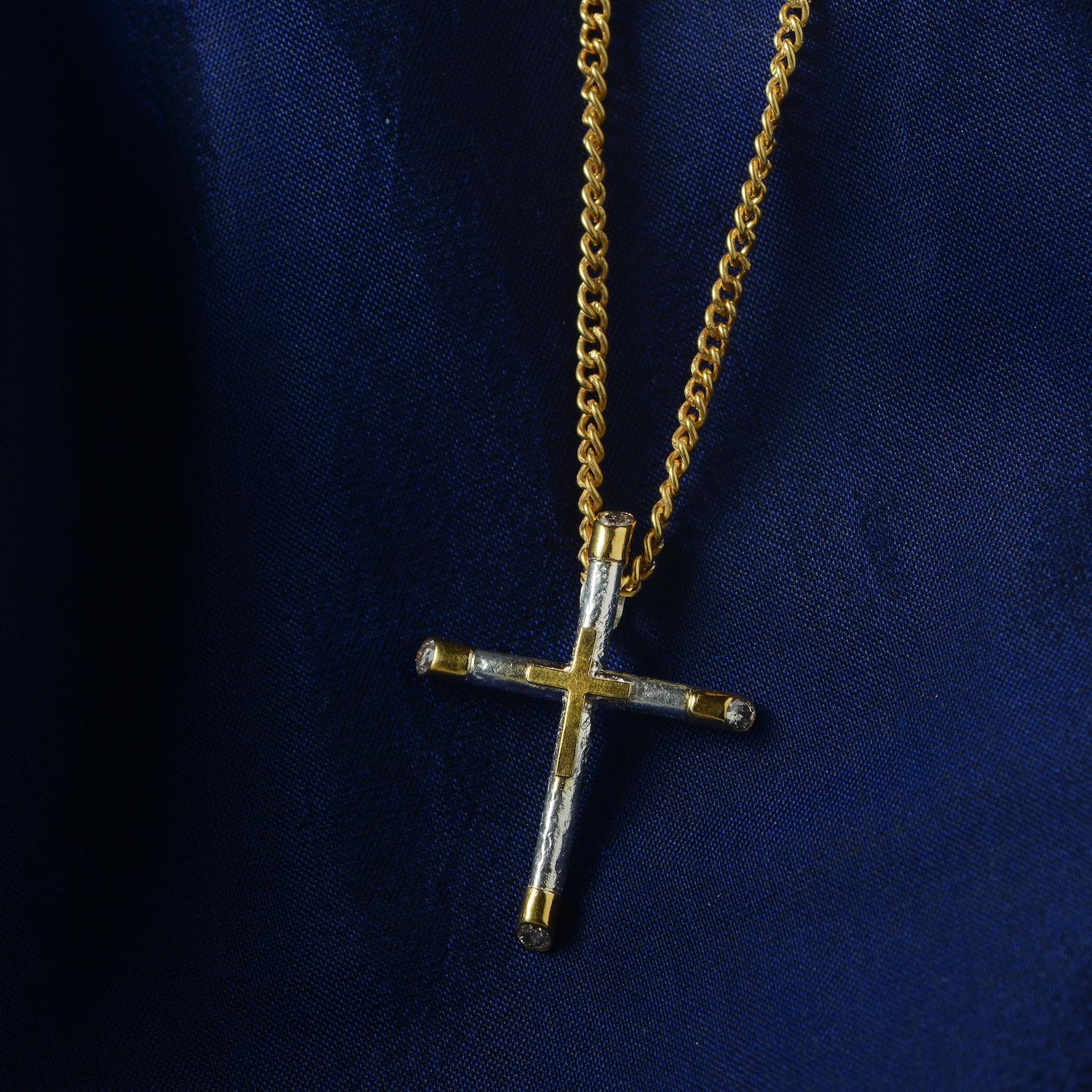 

Uno squisito ciondolo a forma di croce fatto a mano e unico nel suo genere. Questo ciondolo è realizzato in argento sterling leggermente strutturato con decorazioni in oro 18 carati. Ogni punta della croce è incastonata con un diamante a taglio