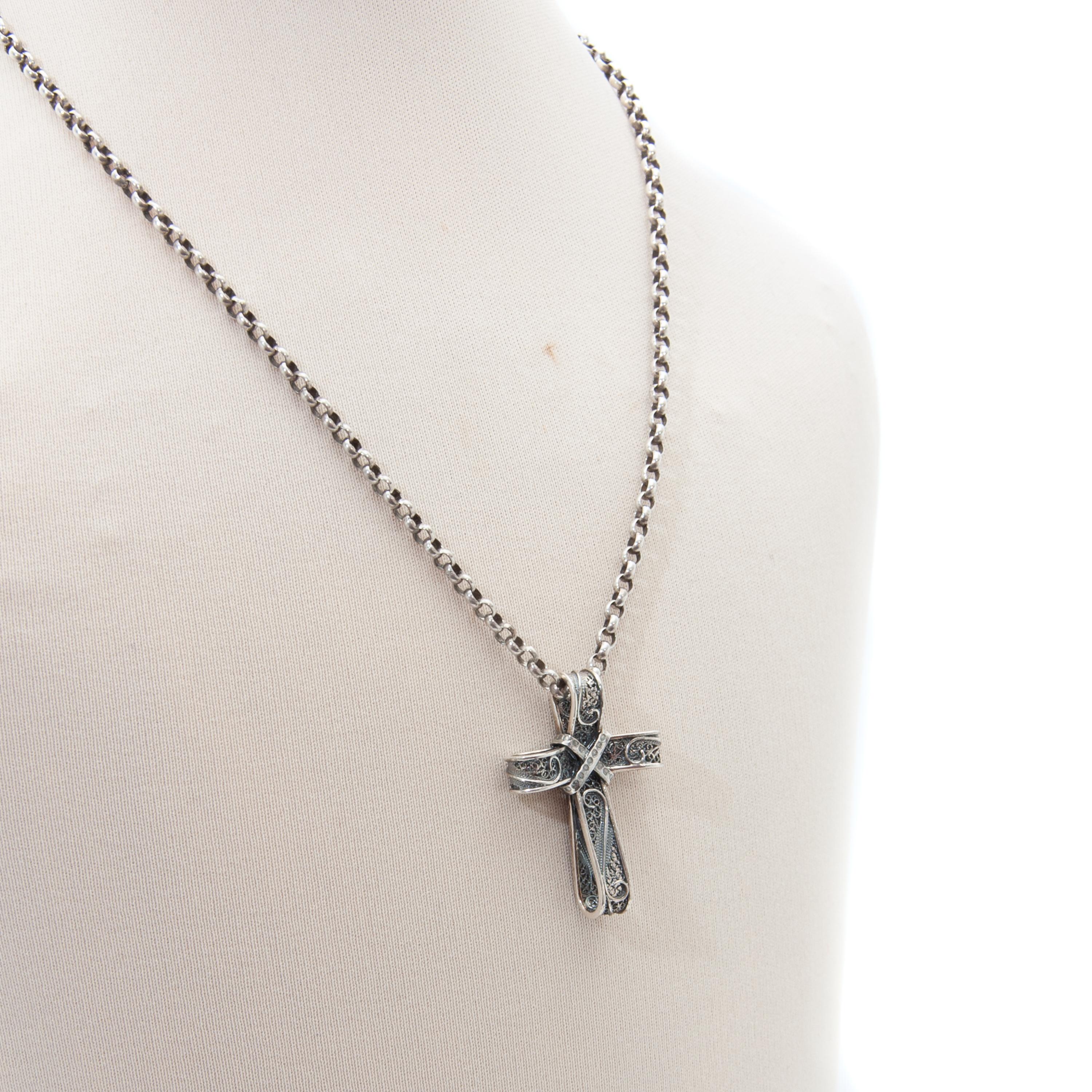 A gorgeous early 20th century cross pendant made of silver. The cross consists of filigree wire work, which is finely crafted by hand into this lovely religious pendant. The edge of the cross is made of smooth silver. The pendant comes without the
