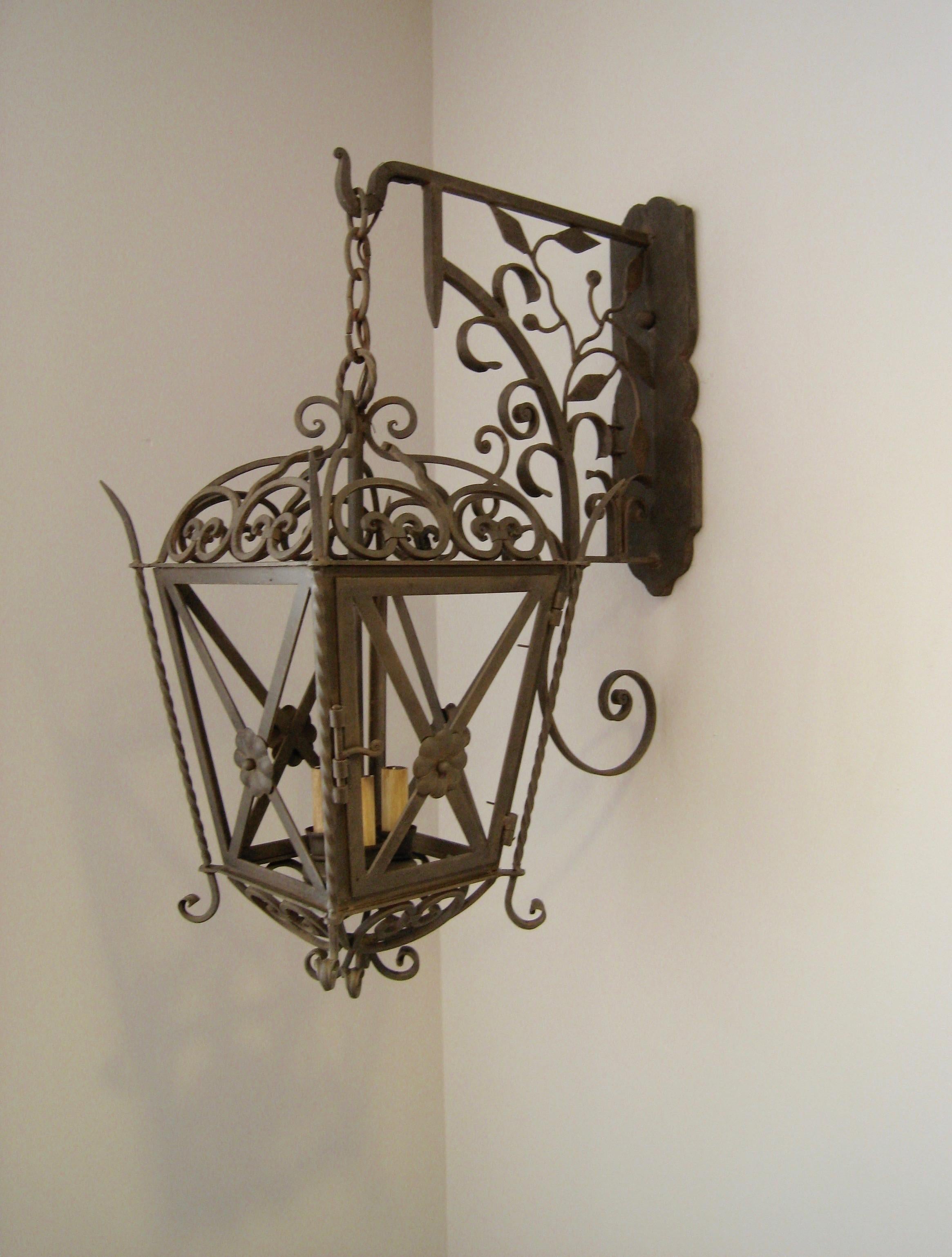 This is our cross and rose lantern on Italian bracket, part of the chandelier product line. The lantern is shown without glass for interior use but requires glass if used for exterior use. Glass options are seeded or clear. Shown in our Antique Rust