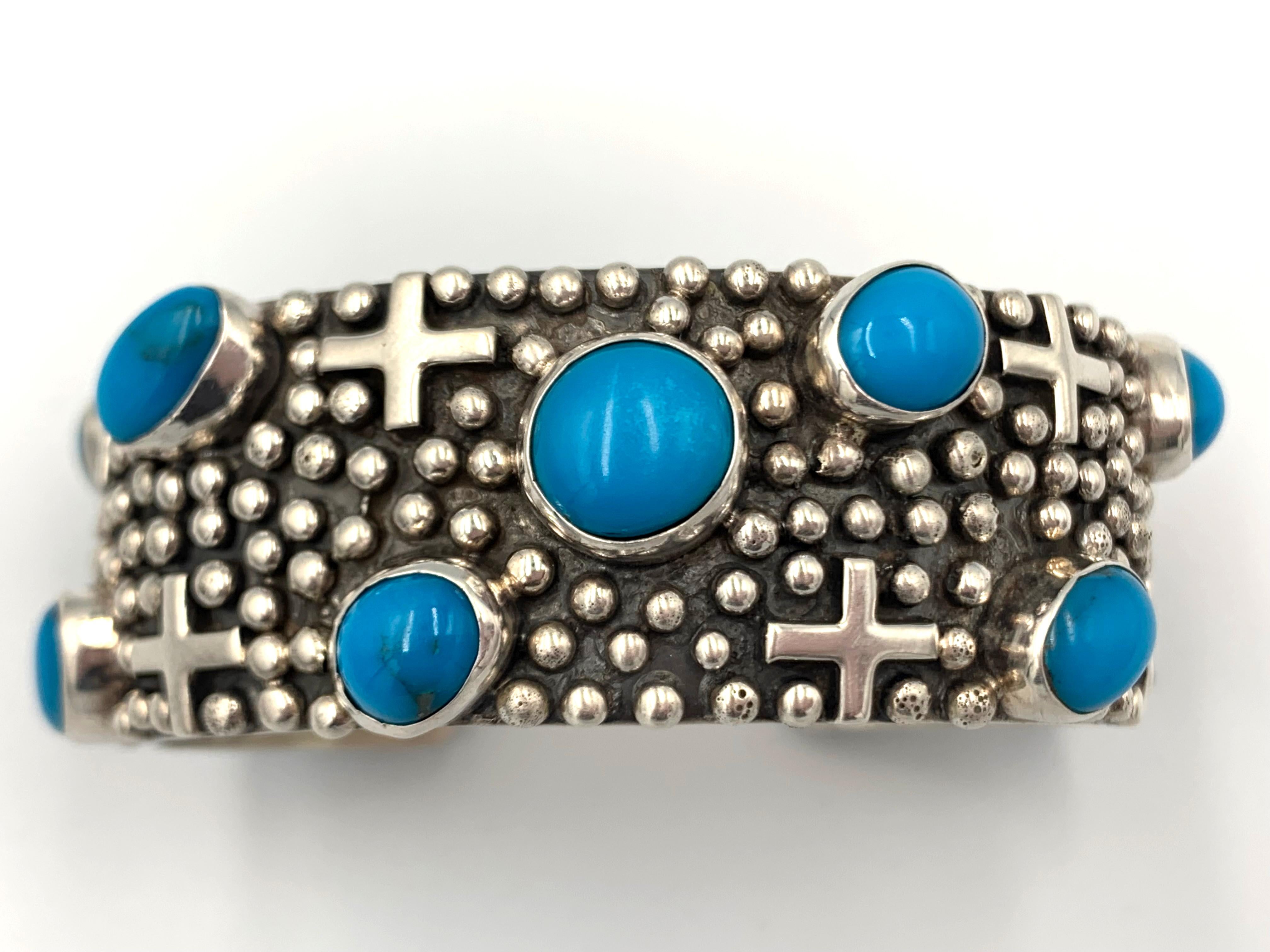 Questo braccialetto è realizzato a mano dall'argentiere Navajo Ronnie Ray Willie. Questo pezzo presenta questo disegno con croci in argento sterling che poggiano sulle perline (gocce di pioggia). L'artista ha incorporato 10 croci e 11 pietre