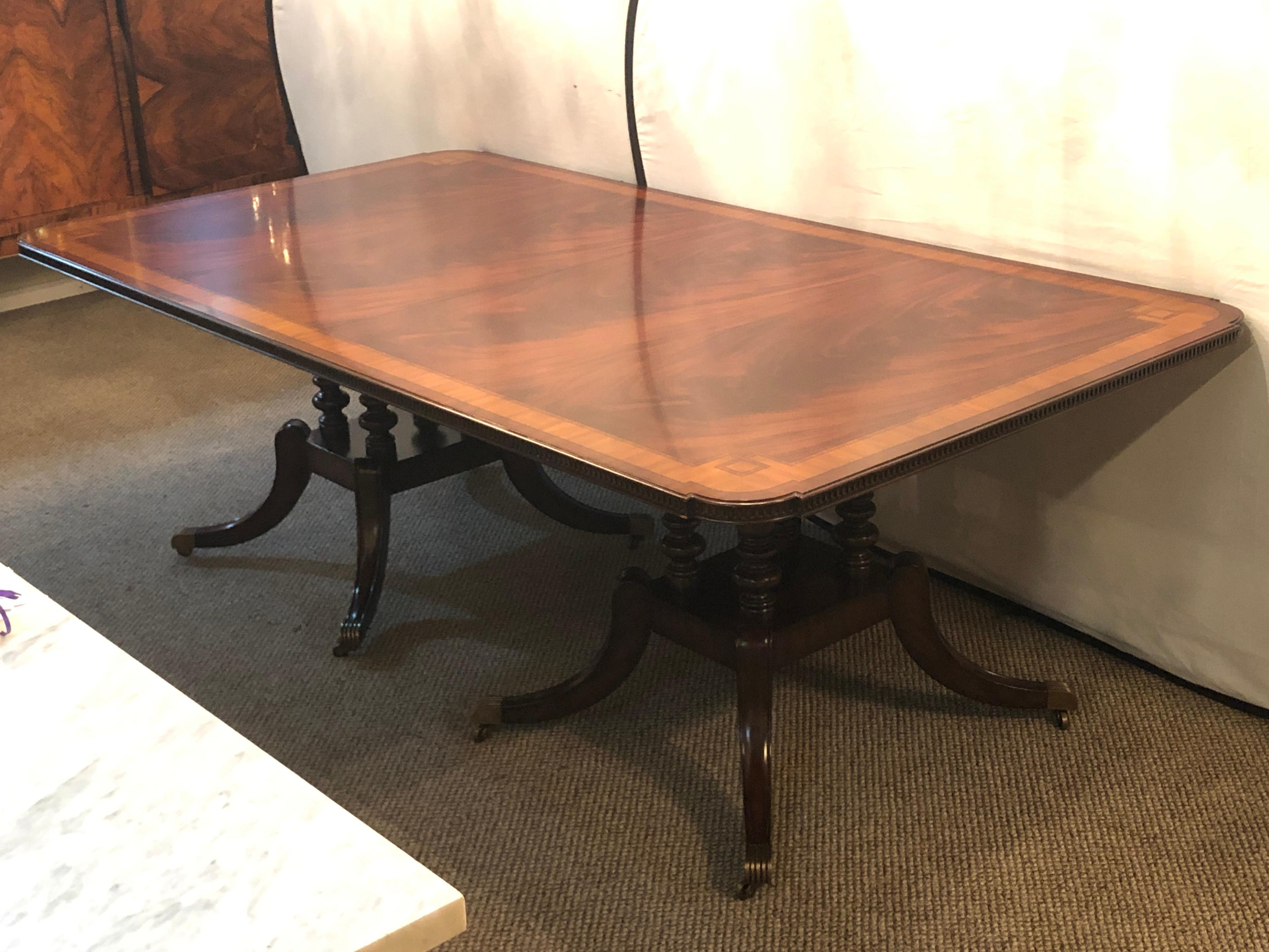 Crotch mahogany satinwood banded double pedestal quad leg dining table with two 21 inch leaves. Fine quad legged base on two pedestals with an amazing table top of ebony and satinwood inlays on a flame mahogany background.

 