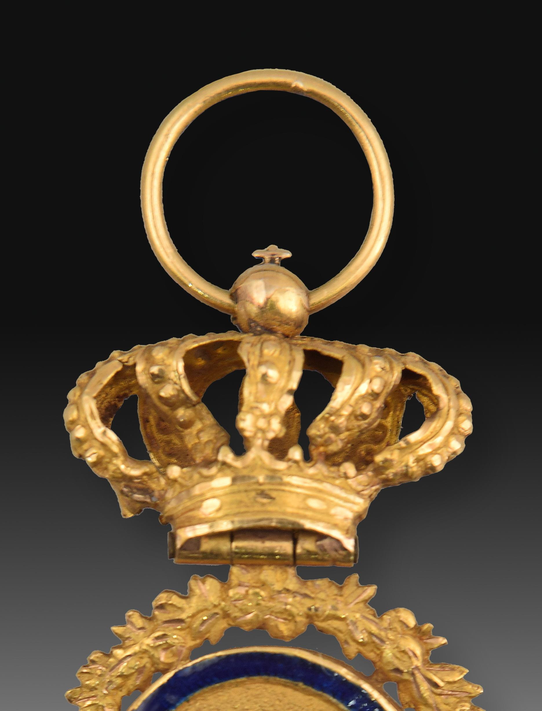 Crown and insignia of the Holy Order of the Inquisition. Gold, enamel. Spain, XIX century. 
Pendant made of gold composed of a ring from which hangs a pierced royal crown to which the body of the medal is attached by means of a hinge. It consists