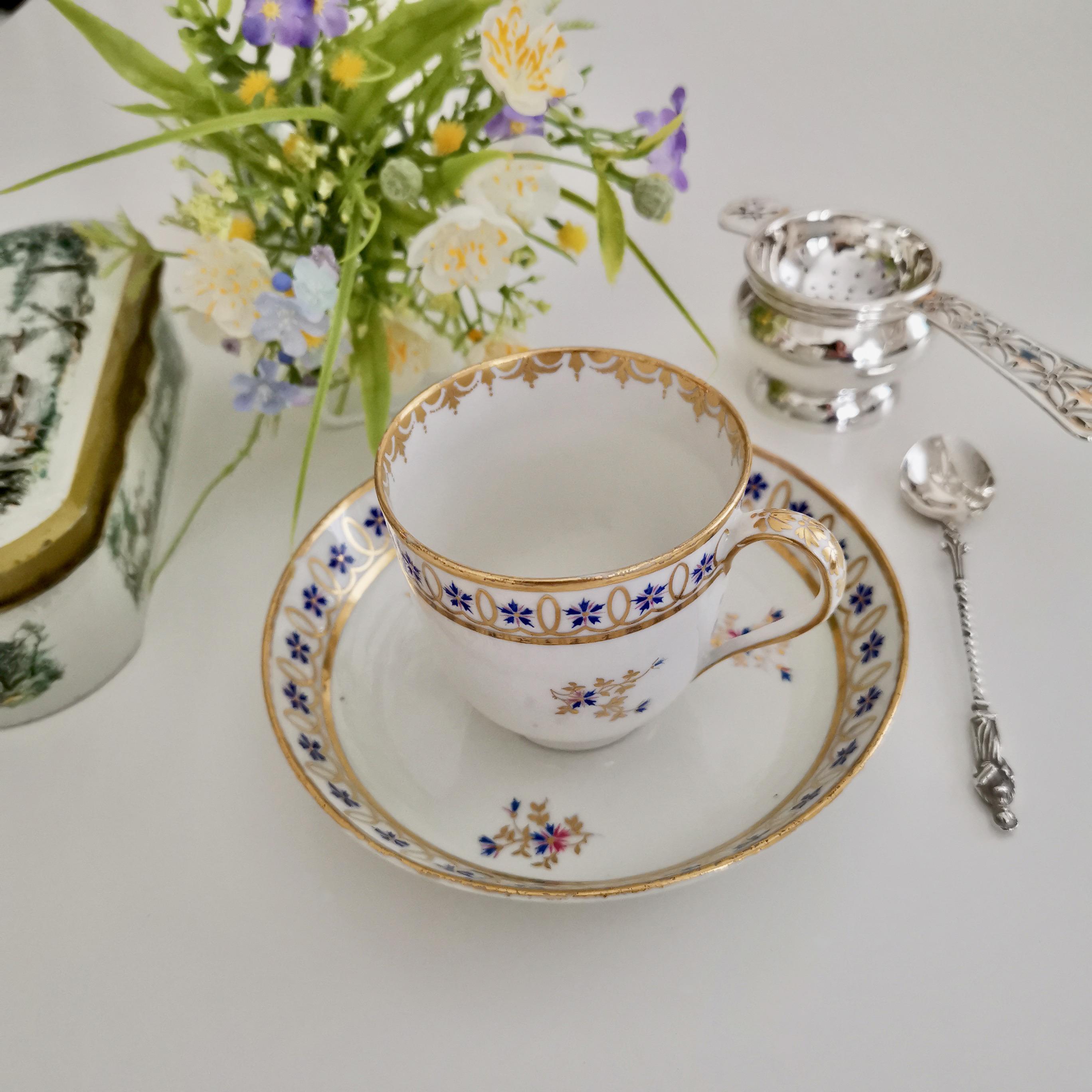 This is a beautiful little coffee cup and saucer made by the Crown Derby Porcelain Company some time between 1782 and 1790. The set has a simple white ground with a gracious pattern of little blue cornflowers set in gilt.

The set was made by the