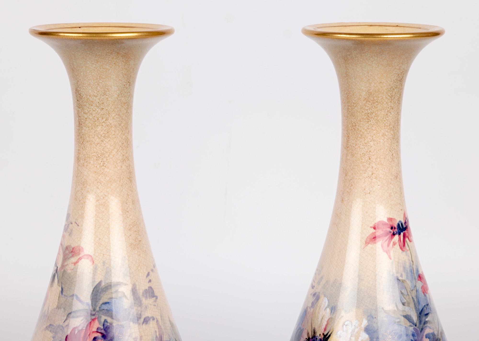 A large and impressive pair Crown Lambeth Ware floral painted vases by a recorded however unidentified artist dating from around 1892. The tall stoneware vases stand raised on narrow round conical feet with tall tear drop shape bodies with trumpet