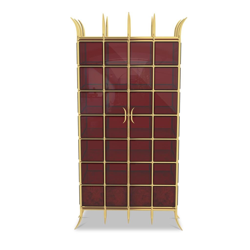 The Crown Jewel Cabinet is custom-made to order. The cabinet is made from brass and ruby red bevelled cut glass. It has Walnut burl veneer on the interior shelves with a lacquered finish. The shelves and drawers are adjustable. This cabinet is a