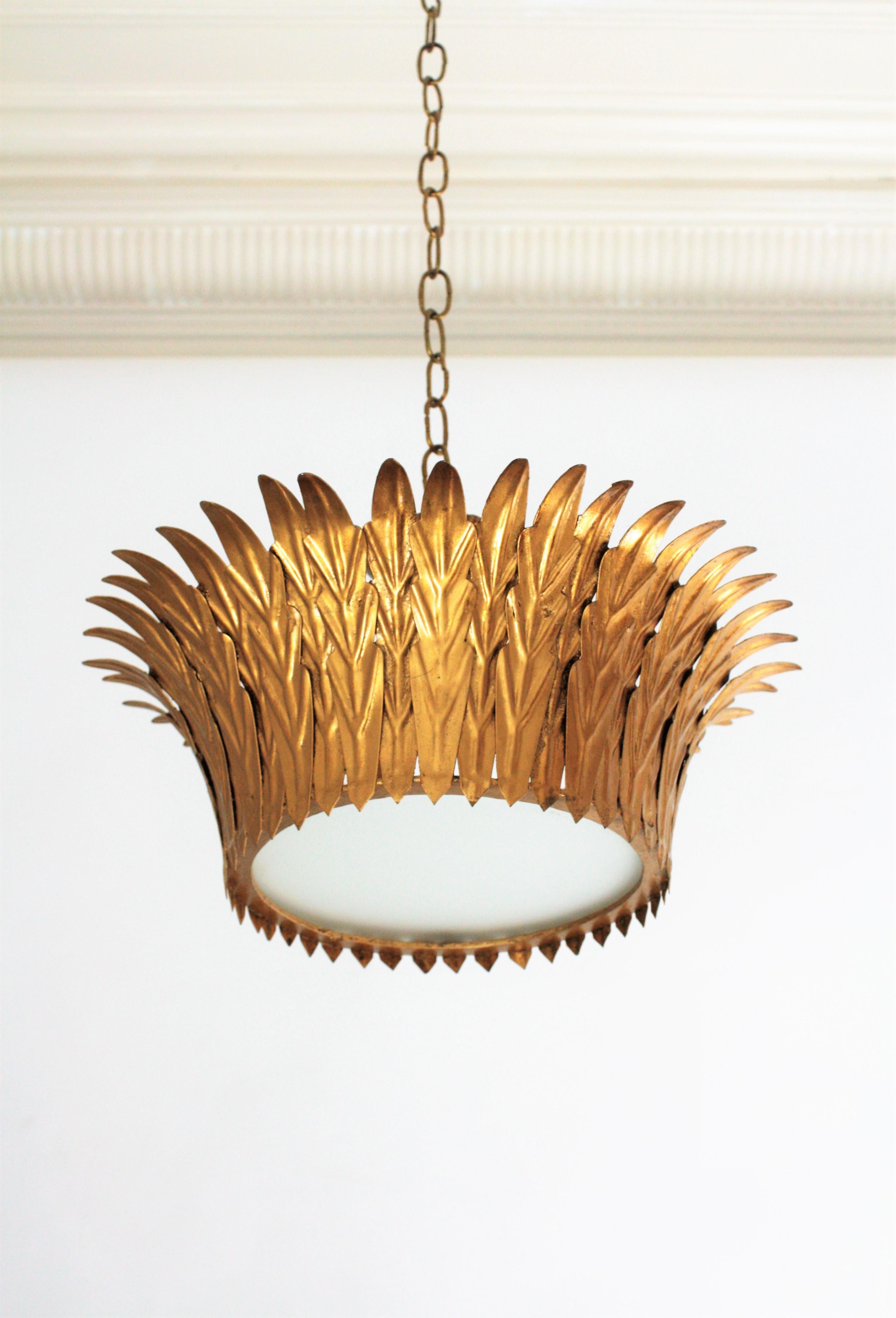 Eye-catching crown shaped ceiling light fixture or pendant in neoclassical style. France, 1940s.
Handcrafted in gilt iron with a foliage frame surrounding a central frosted glass panel.
It can be used flush mounted or as a pendant hanging from a