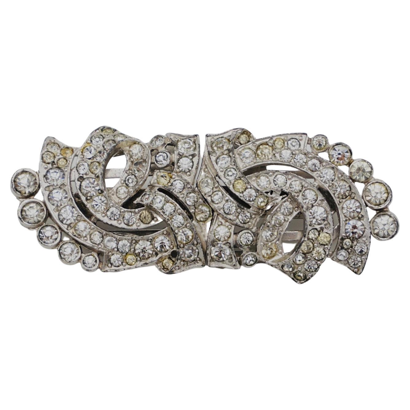 Les bijoux fantaisie Trifari de la fin des années 1930 comprenaient des Clip-Mates, leur version de la broche à double clip. La monture est plaquée rhodium. Cette pièce peut être portée comme une broche ou comme deux clips de robe séparés. 

Bon