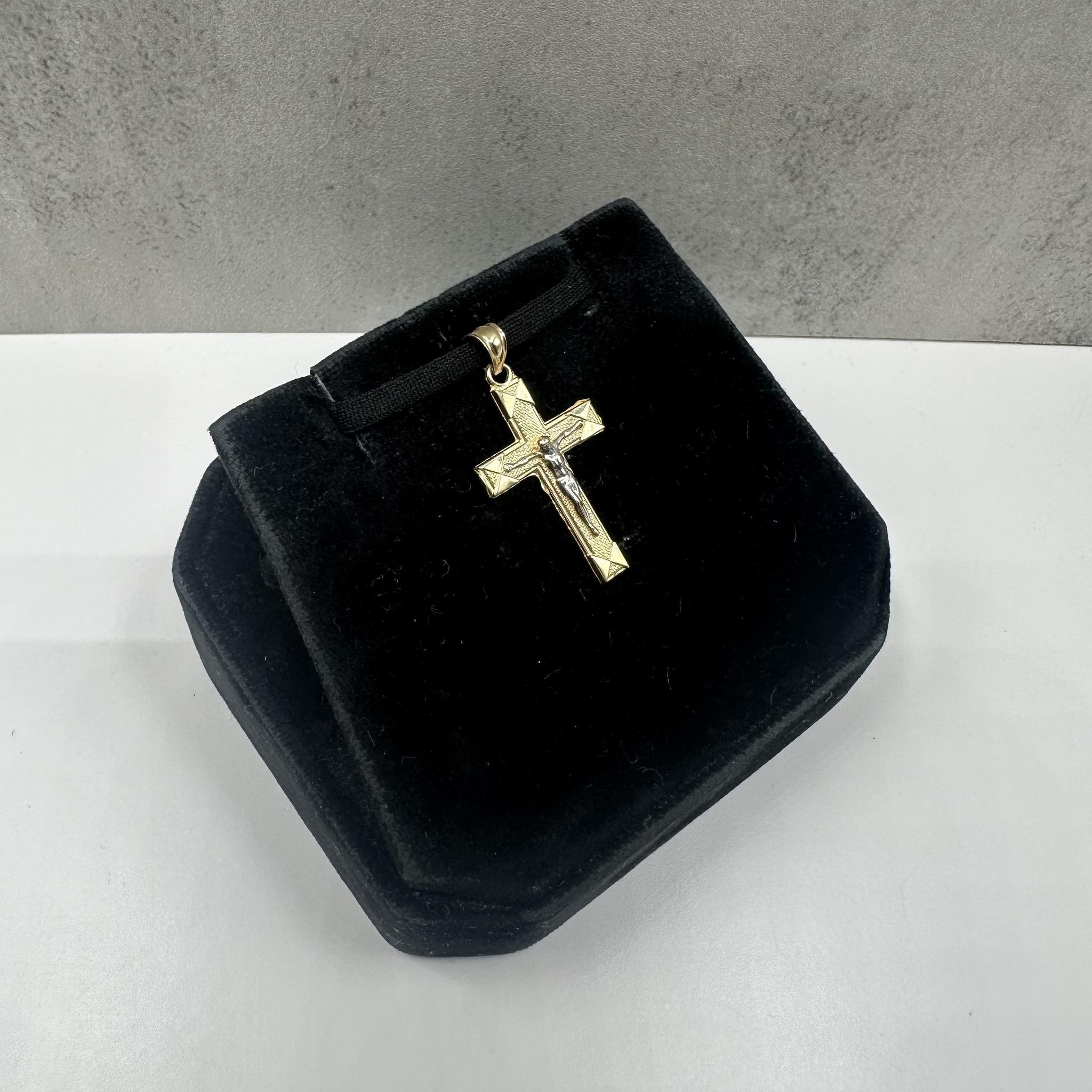 Este elegante colgante crucifijo de oro bicolor de 14 quilates presenta una refinada combinación de acabados amarillo y blanco que resaltan su detallada artesanía. Los tonos contrastados añaden profundidad y brillo, dando a este diseño clásico un