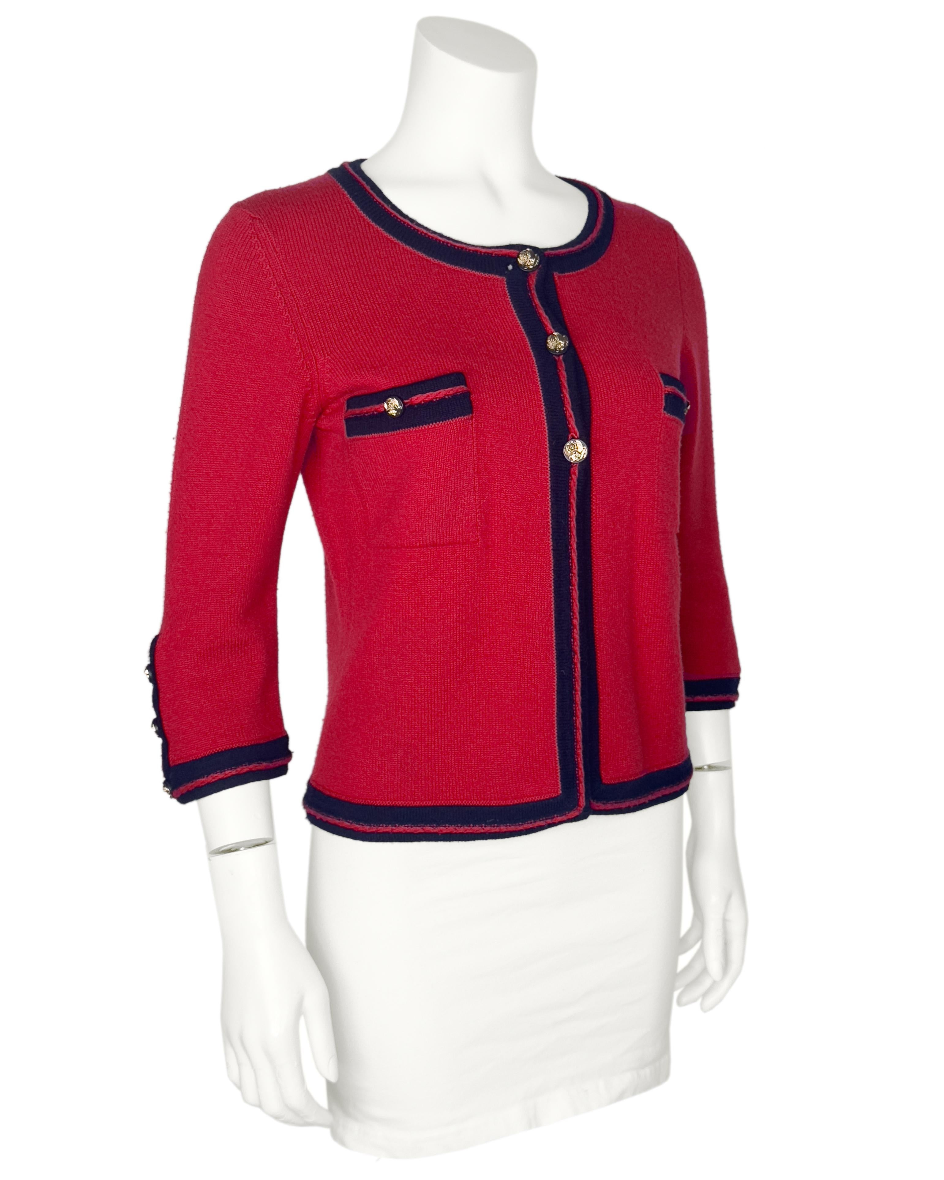 Chanel Cruise 2010 collection red cashmere sweater with navy trim. The sweater is designed as a classic Chanel jacket with front patch pockets and matching buttons on the cuffs. The black and gold tone button feature several Chanel symbols including