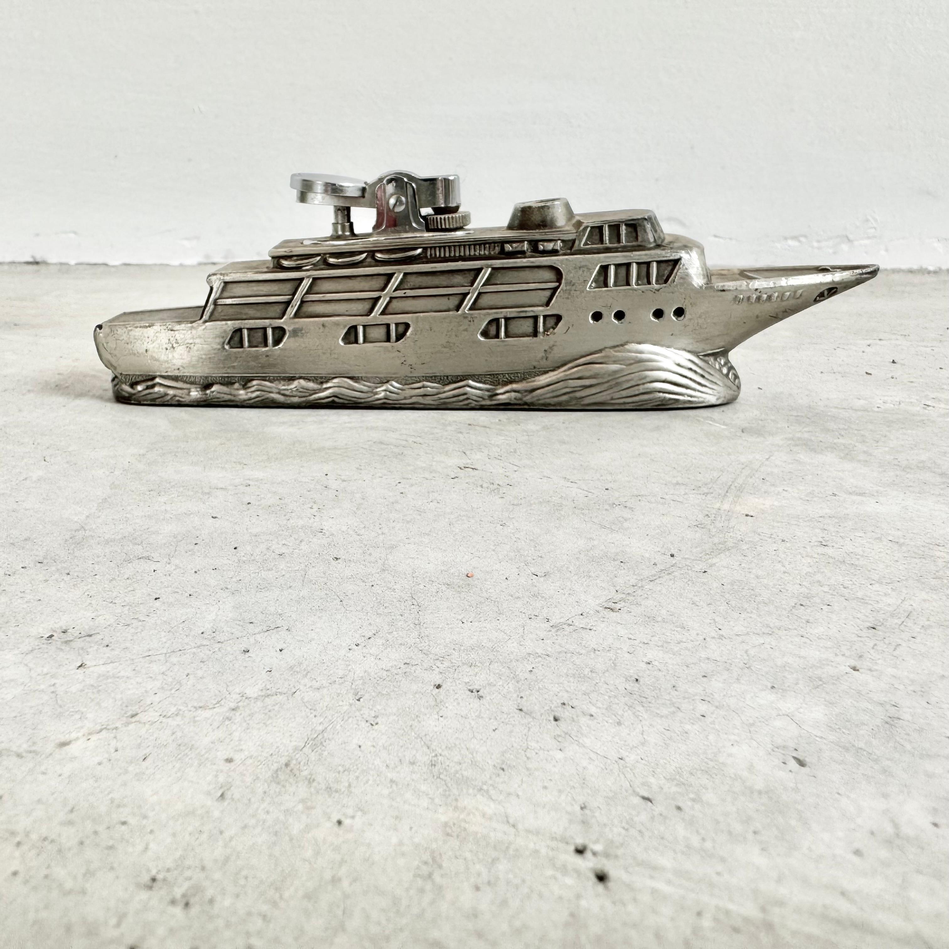 Einzigartiges Tischfeuerzeug in Form eines Kreuzfahrtschiffes, das sich an seinem Bug in den Wellen teilt. Hergestellt in Japan, 1980er Jahre. Ein lustiges Feuerzeug, das für jeden Liebhaber der Schifffahrt perfekt ist. Mit Gravuren von 2 Ankern auf