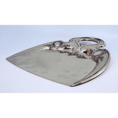 Crumb catcher in embossed silver with floral motifs surrounding monogram cards