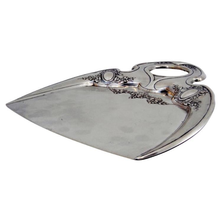 Crumb catcher in embossed silver with floral motifs surrounding monogram cards