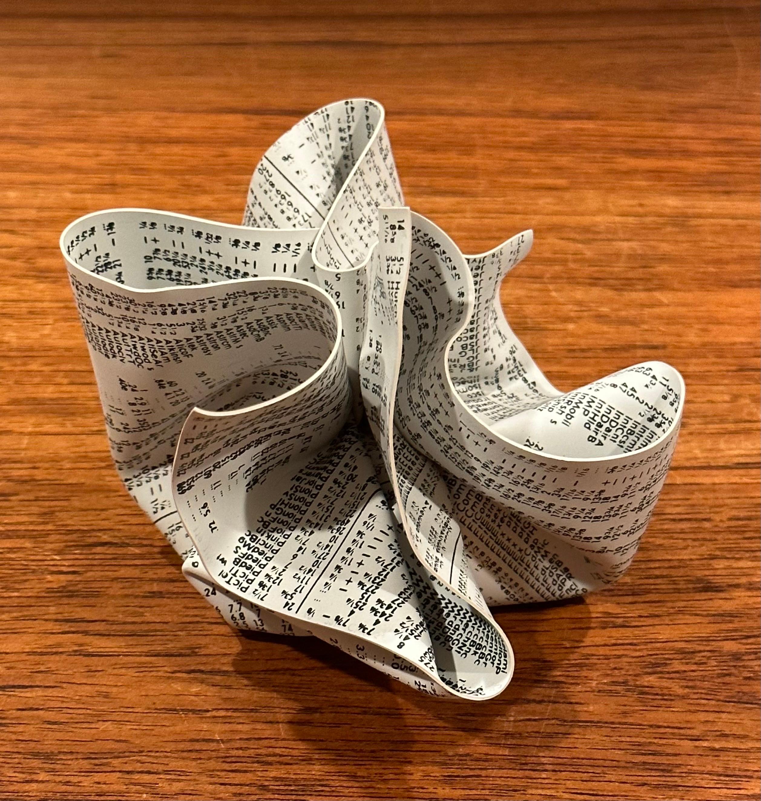 A very cool crumpled WSJ / newspaper paperweight by designer Tibor Kalman for M & Co. and MOMA, circa 1980s.  This three-dimensional art object is made of rigid silk-screened vinyl featuring a stock exchange newsprint, hand-crumpled, and wrapped