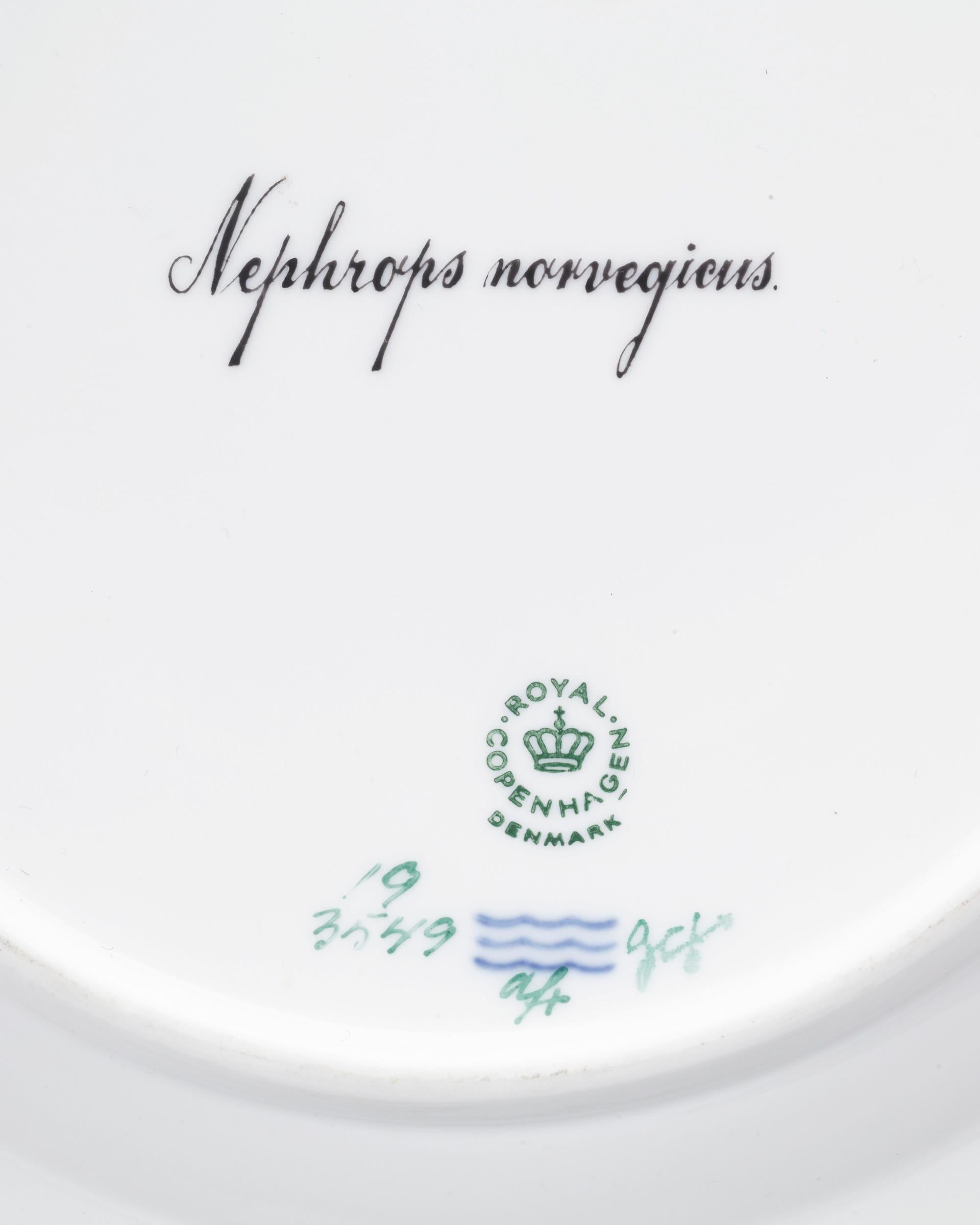 This hand-painted porcelain plate by Royal Copenhagen is adorned by the firm's highly regarded Flora Danica pattern. While the majority of the motifs in the Flora Danica pattern capture the native fungi and flowers of Denmark, this plate is part of