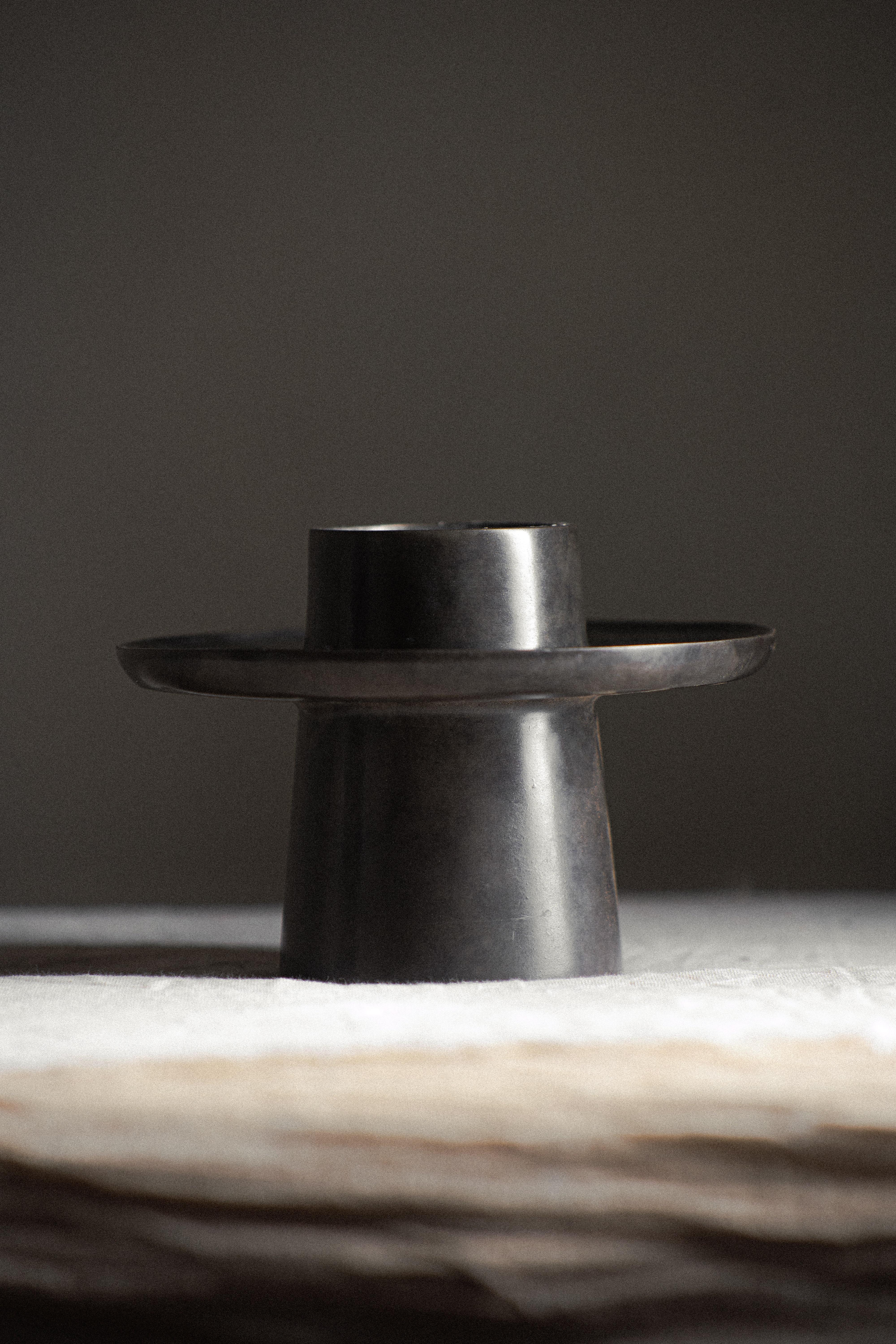 Crypt Candle Holder by Atelier ACM
Dimensions: D 14 x W 14 x H 12 cm.
Materials: Bronze, silver nitrate patina.

Our collection stands as a reaction against the mass-produced world we live in where people no longer value objects, advocating for a