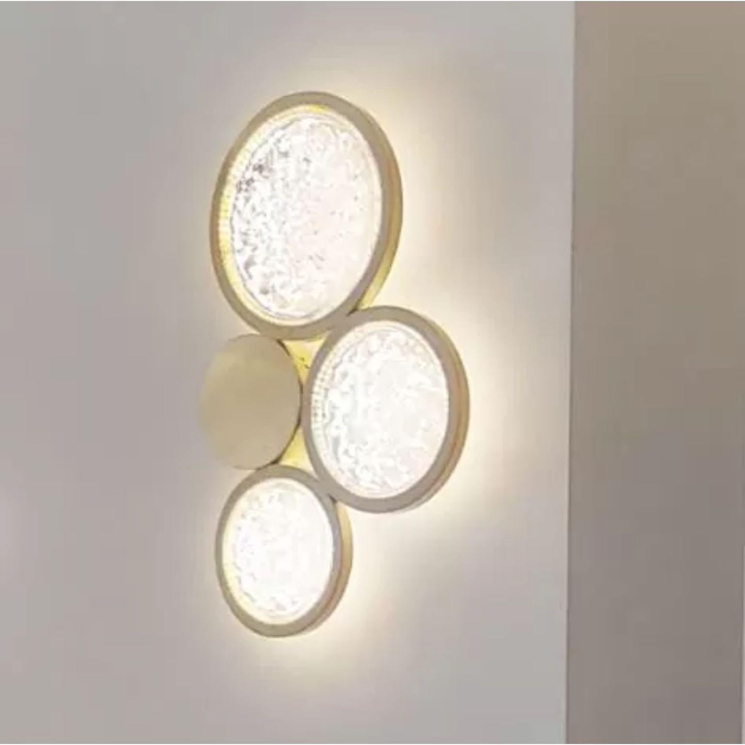 Crystal and Brass Circles Wall Sconce by Dainte
Dimensions: Ø 37 x H 58.5 cm.
Materials: Crystal and brass. 

A unique brass wall sconce that consists of three circles of glistening textured crystal plus one circle of Brass all joined together in a