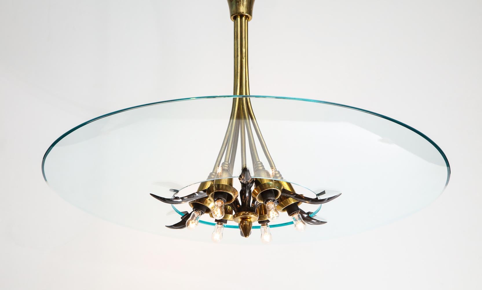Large, slumped crystal dish with a central opening. Supported by a brass structure of sculpted leaf forms and polished brass rods. Six-light sources.