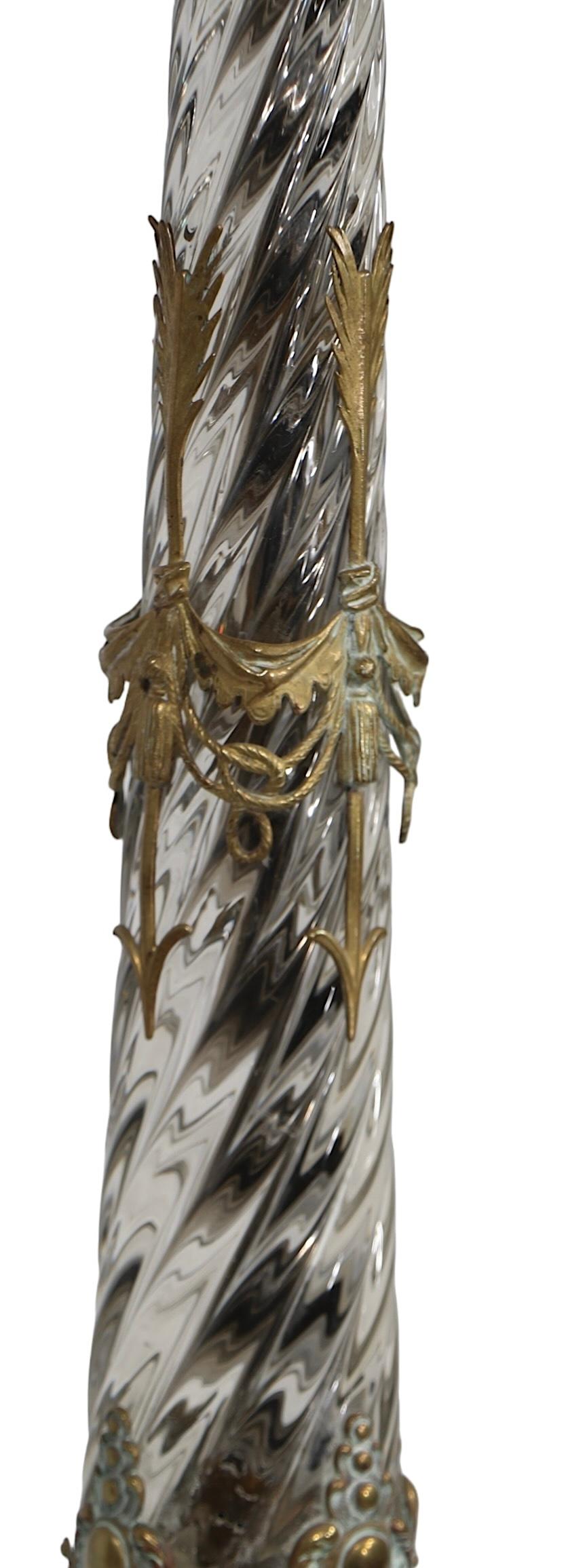 Exceptional tall glass table lamp, attributed to Baccarat. The lamp features a tall tapered glass body with twisting  swirled surface, with decorative cast brass elements. The center of the lamp has a brass arrow and swag mount, the base is cast