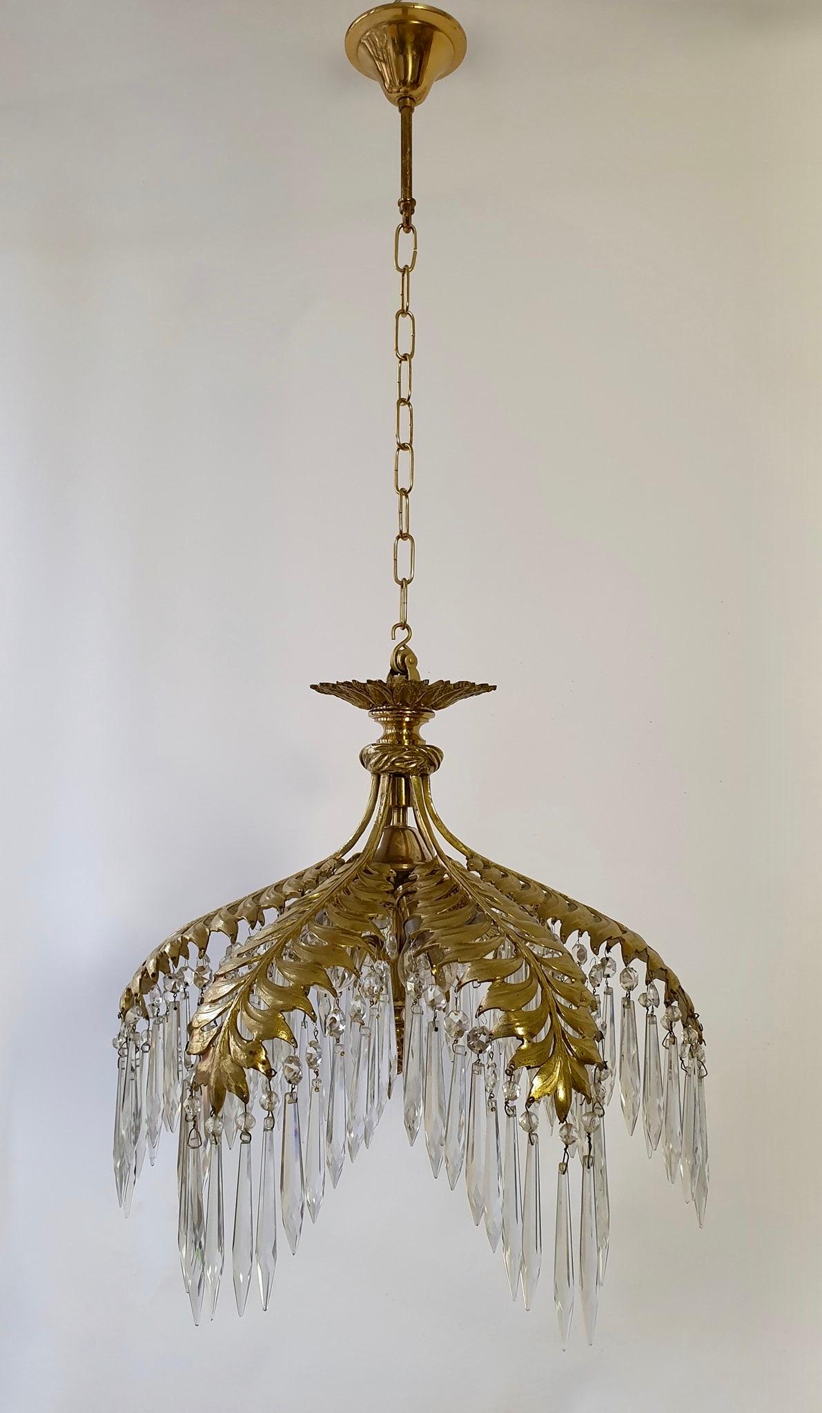 Superb gilt bronze chandelier with issuing elegant leaves from which hang cut-crystal pendants and hiding six-light.
Glamorous Maison Jansen bronze palm frond chandelier with crystal cones, circa 1920s. Retains warm original patina. Maison Jansen