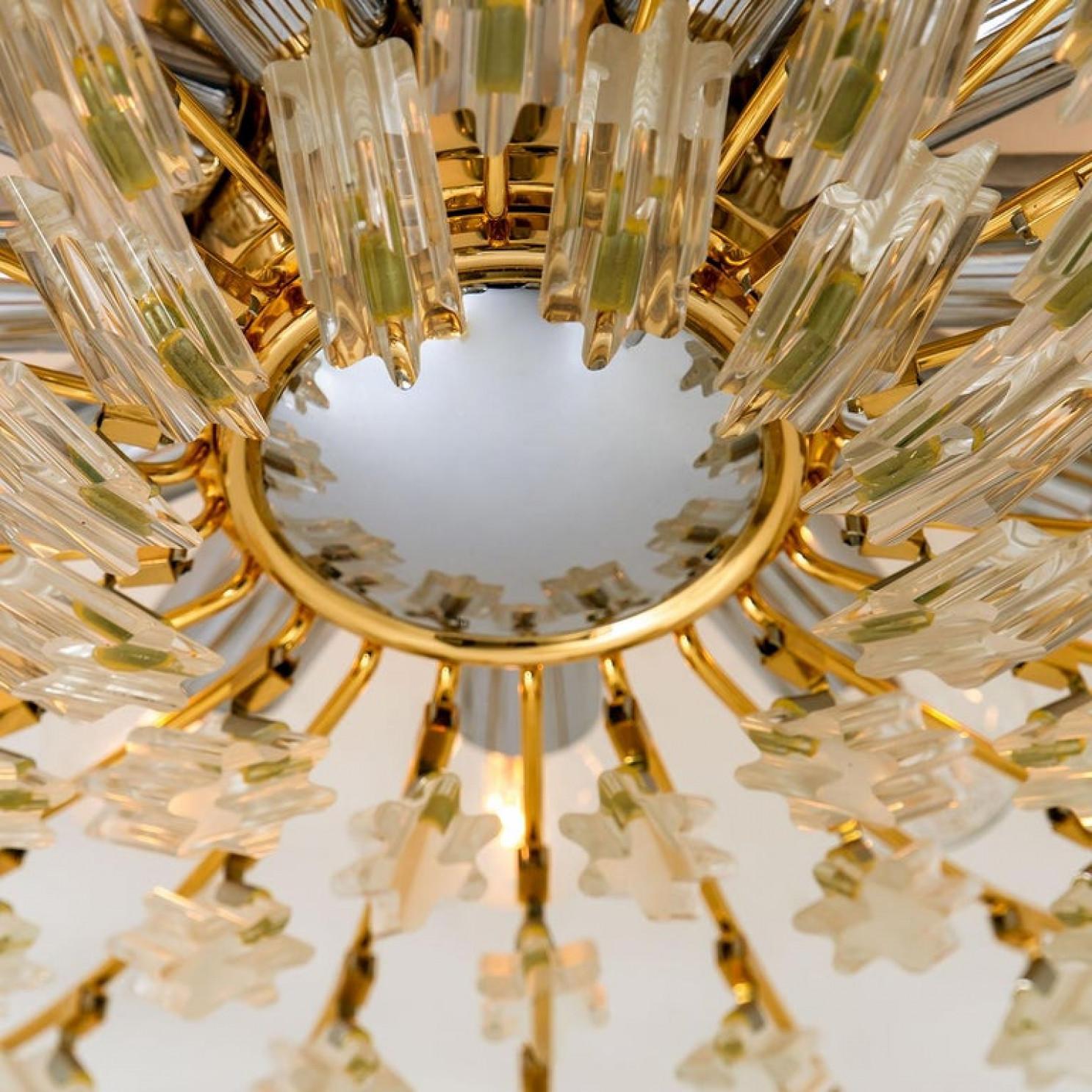 High-end gilded brass flush mount by Stilkronen, made in Italy, circa 1975, featuring a sunburst array of branches holding 30 clear crystals pieces. The crystals refract light beautifully and are perfect for a soft, warm and welcoming glow in the