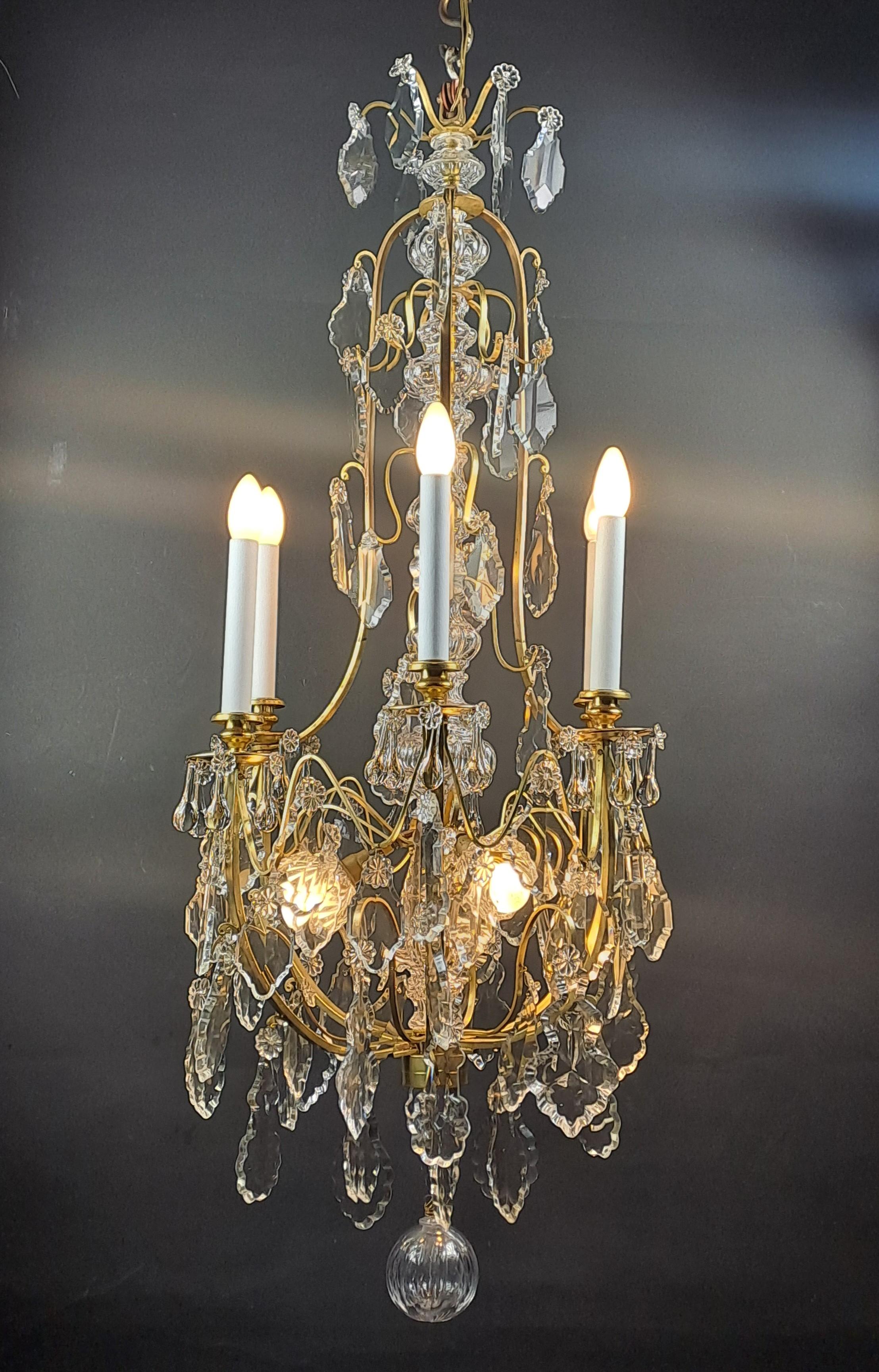 Very elegant gilt bronze cage chandelier with rich and generous crystal ornamentation composed of large cut plates, crystal water drops around each bobeche and a long molded shaft.

Illuminated by six light arms and three interior lights.

Work of