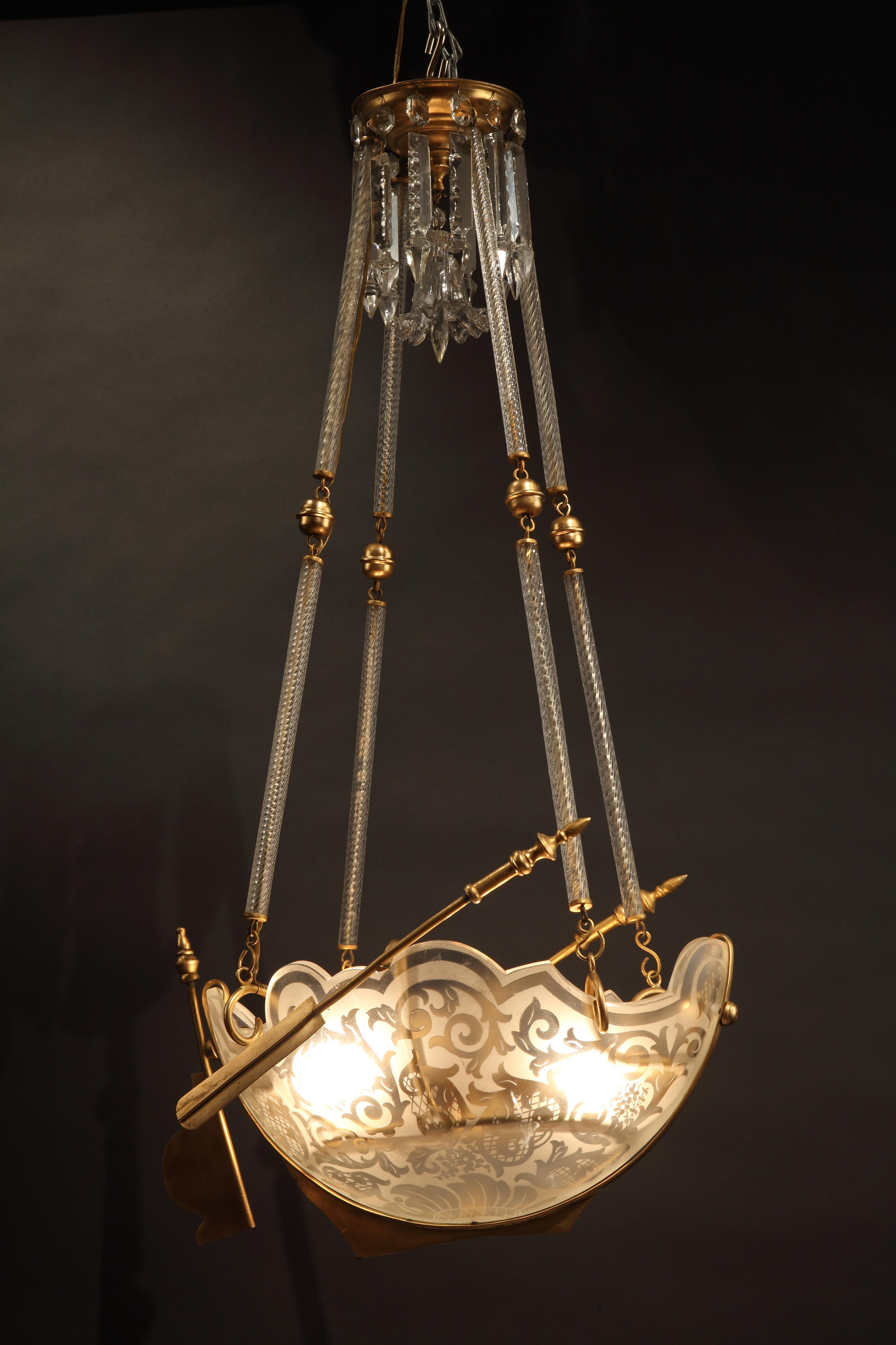 Magnifique lustre en forme de vaisseau en bronze doré et cristal gravé attribué à Baccarat, suspendu par quatre chaînes articulées. Un pendentif de plafond décoré de prismes et d'une cloche centrale en cristal ciselé vient compléter le lustre.

La