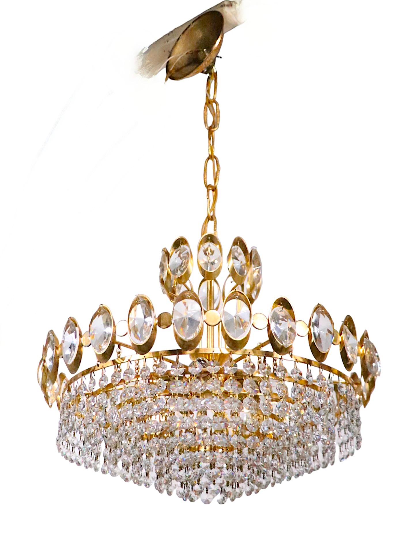 Exceptional Hollywood Regency style chandelier having a gold colored metal frame, with faceted glass jewels, from which hangs graduated concentric rings with prismatic glass strands. When lit, this fixture glistens, creating a warm and elegant