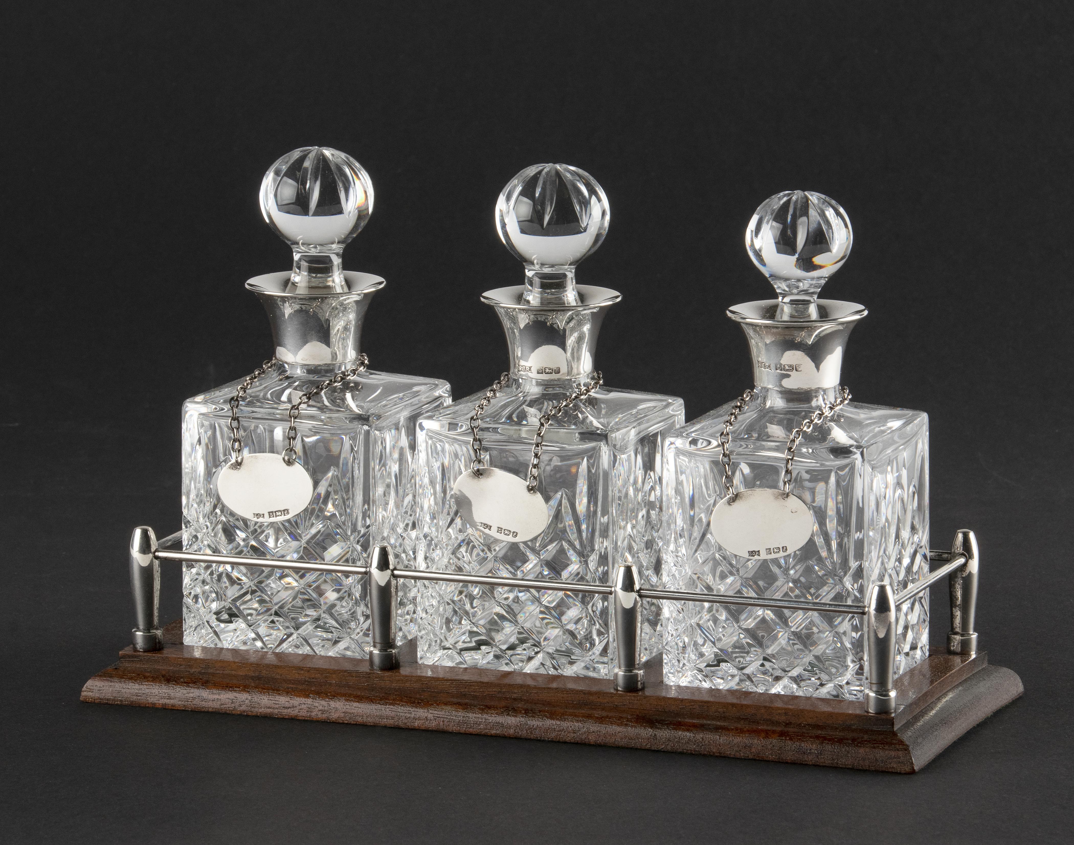 Beautiful liqueur set from England. It is a wooden rack with silver plated railing, containing 3 crystal bottles with sterling silver necks. Each bottle has a sterling silver emblem, which can optionally be engraved with names of, for example,