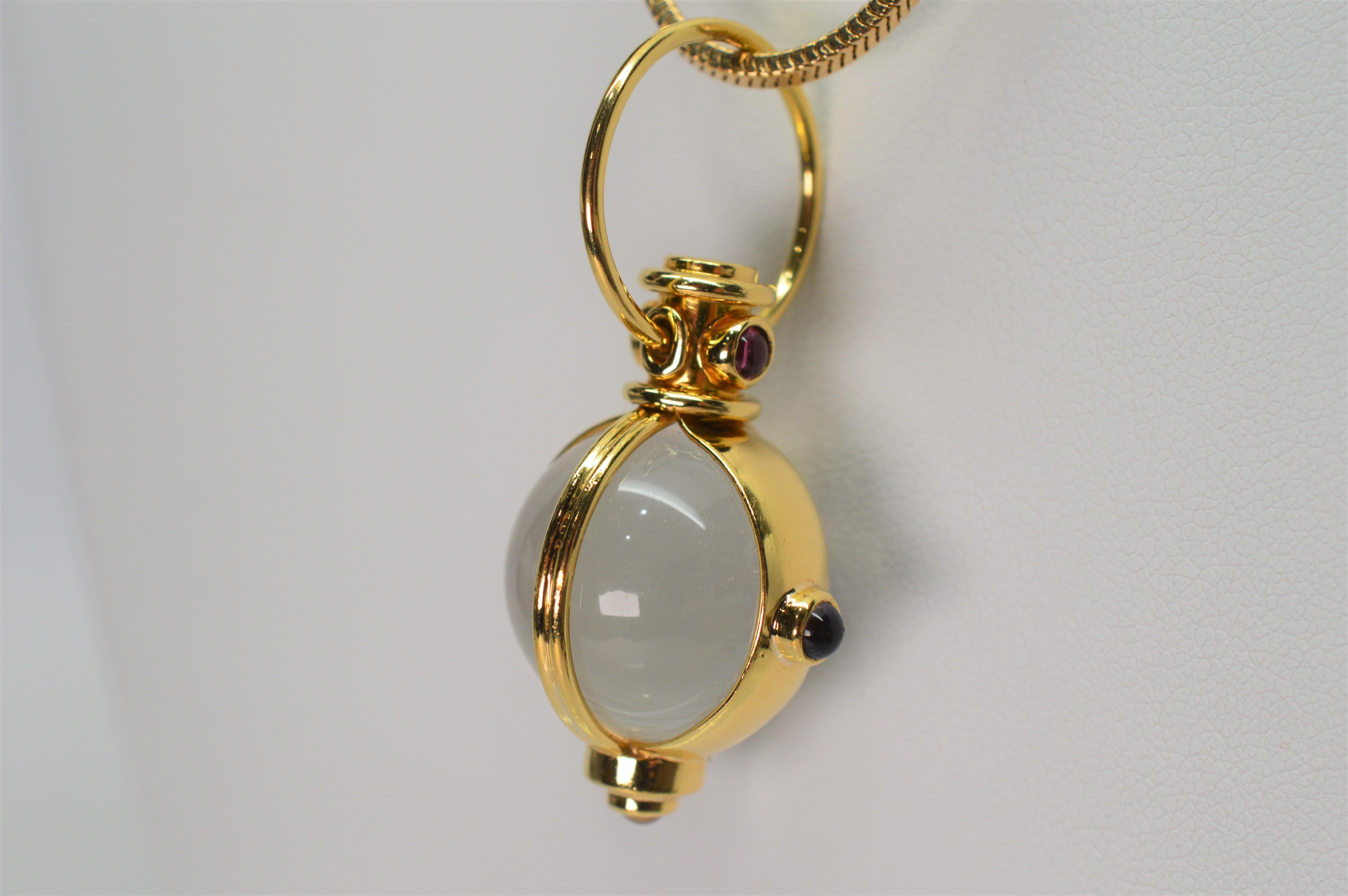 Feel the mystic of this quartz crystal sphere secured in a Gothic inspired eighteen karat (18K) yellow gold charm pendant adorned with rivets of quartz, peridot and amethyst gemstone. The brilliant pendant plays with light as it suspends on a