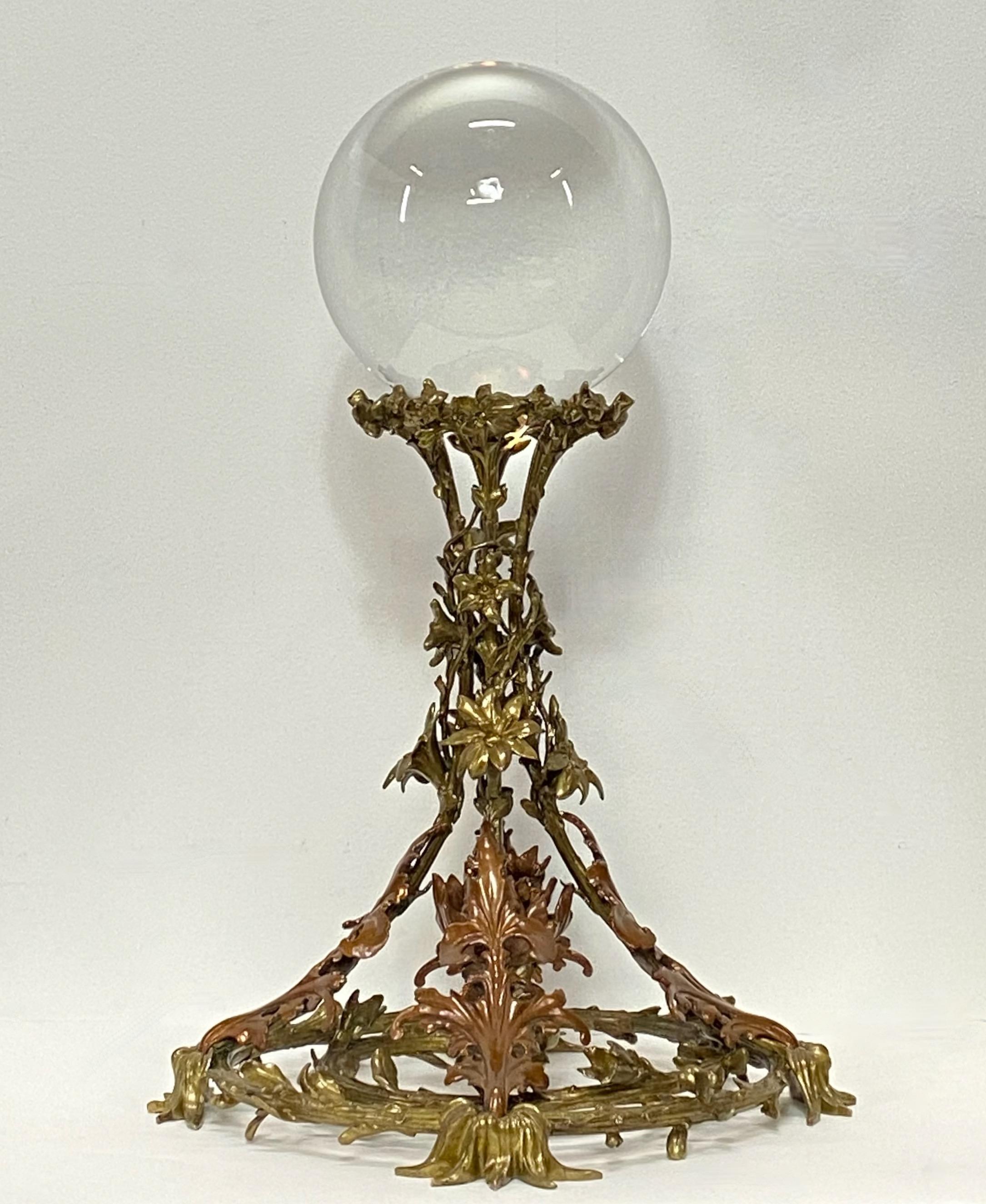 A large crystal ball presented on a unique one of a kind elaborately cast bronze base. This beautiful late 19th-early 20th century base is an unusual two-tone red and gold bronze color with flowering vines.
The crystal ball measures 8 inches in