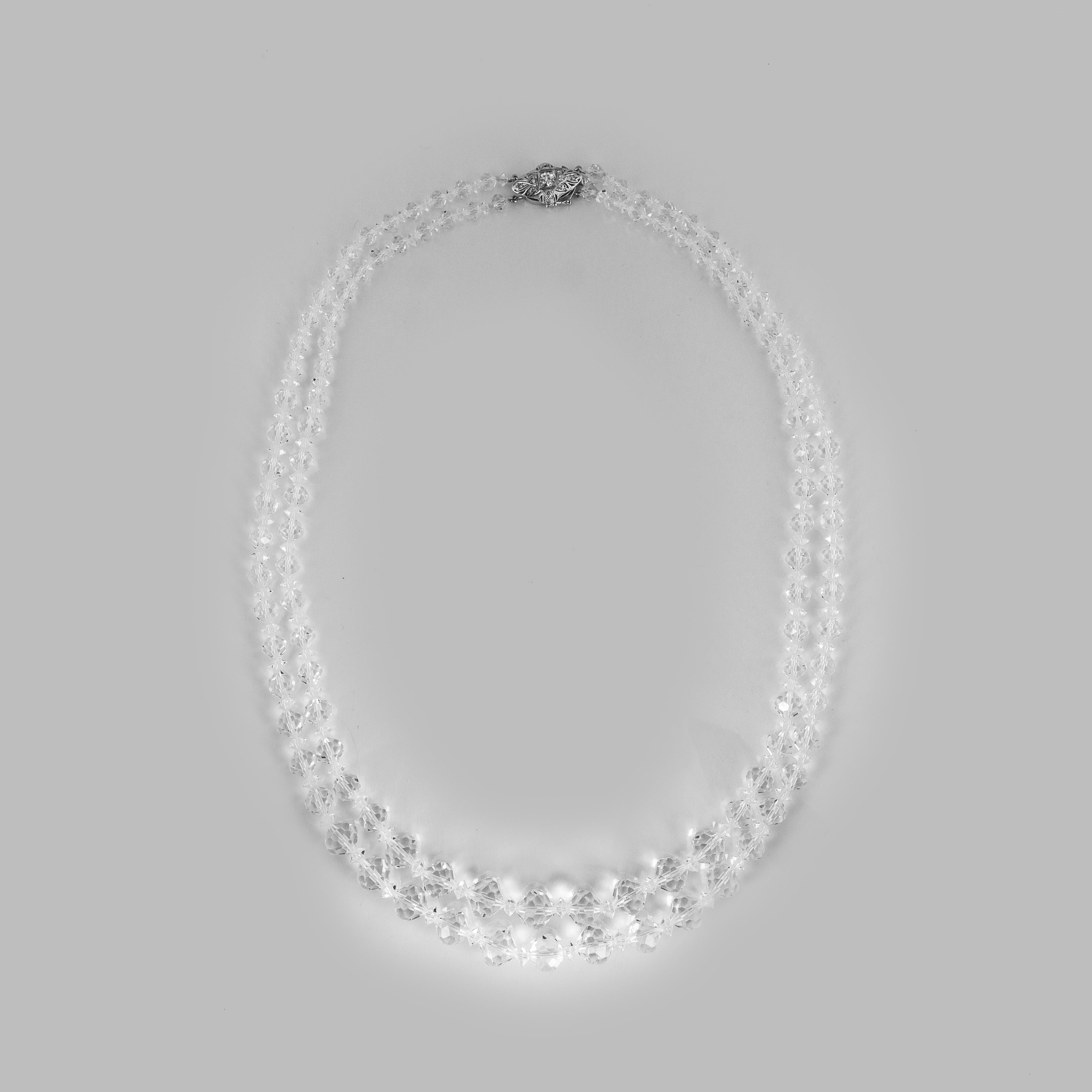 A double strand necklace featuring crystal beads with a platinum and 14K white gold clasp.  The top of the clasp was composed from a vintage platinum bridge ring with 1.10 carats of diamonds.  This necklace measures 25 inches in length.