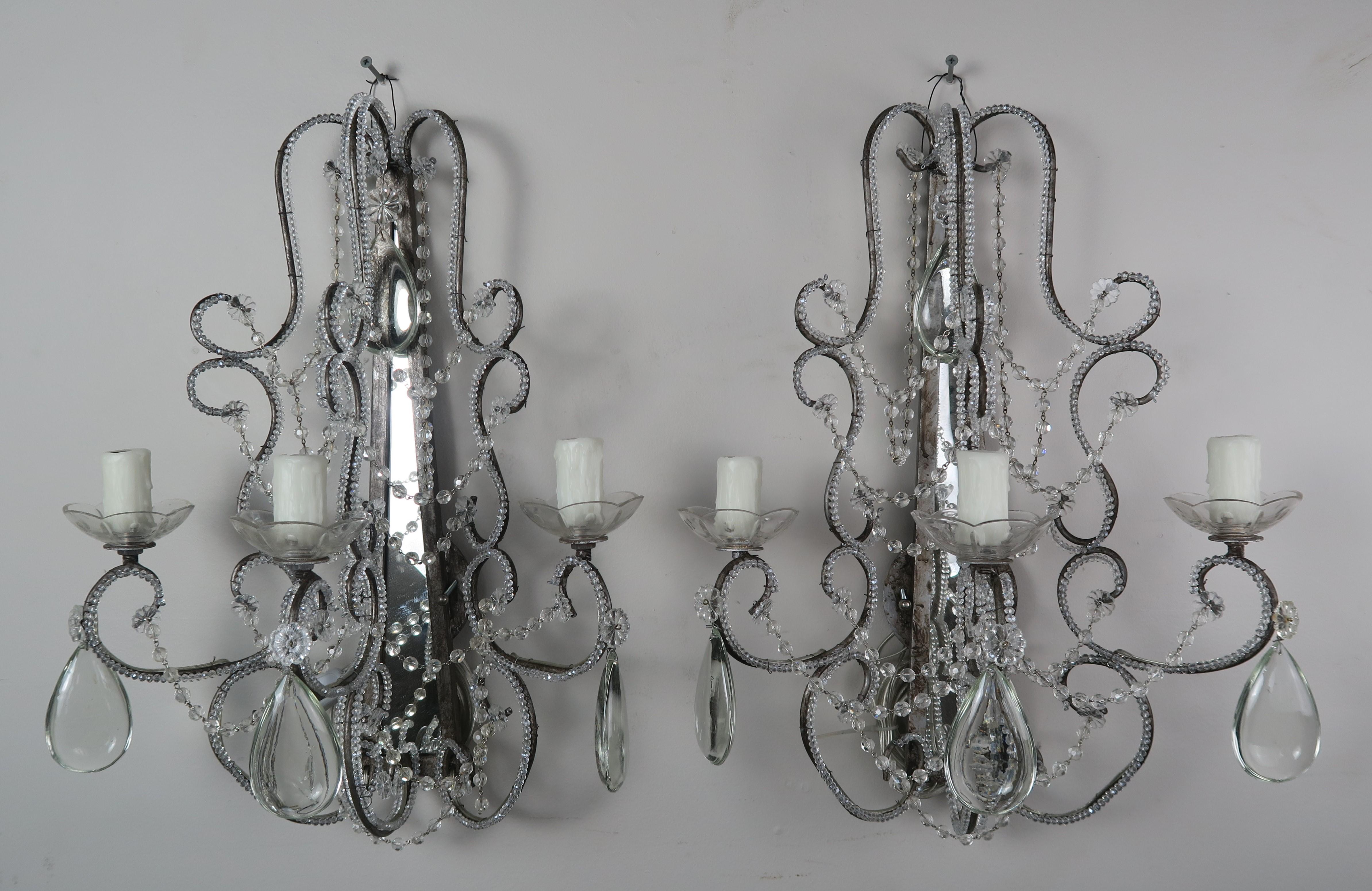 Pair of crystal beaded mirrored back Italian style 3-light sconces with smooth almond shaped crystals. The sconces have been newly rewired with drip wax candle covers and are ready to install.