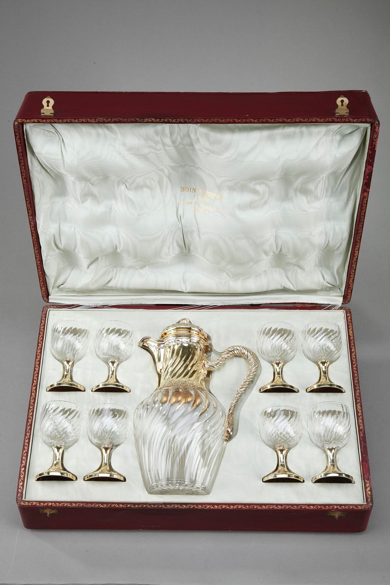 Cut-crystal beverage service with silver-gilt mounts by Maison Boin-Taburet. It is composed of an ewer and 8 glasses highlighted with twisted flutes. The silver-gilt mounts are also decorated with twisted pattern and foliage in Louis XV-style. The