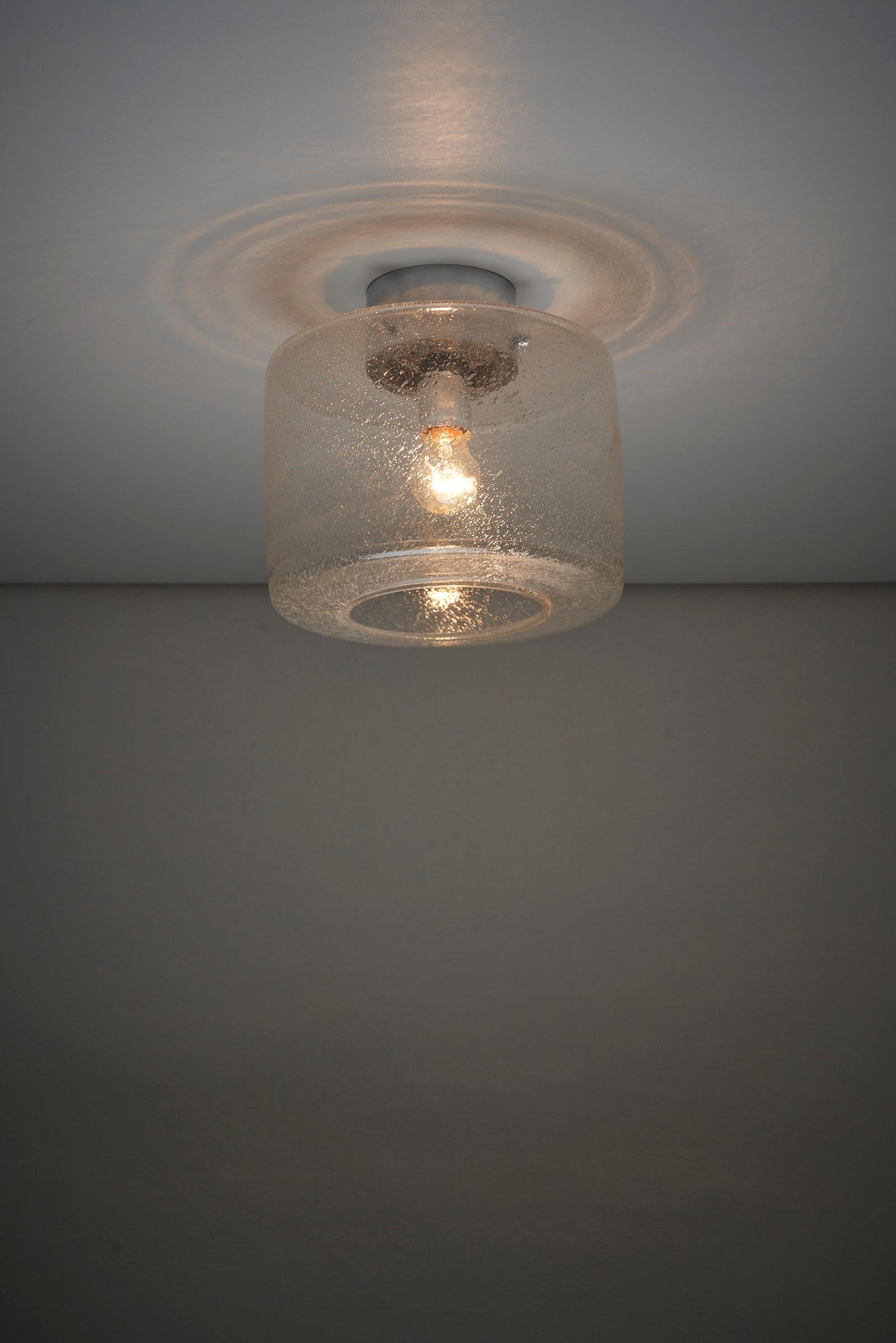 Plafonnier en verre Crystal Bubble de Glashütte Limburg. Ce support de plafond présente un verre texturé de forme cylindrique avec une ouverture en bas, solidement fixé par un système de montage chromé. La lampe conserve son étiquette d'origine à