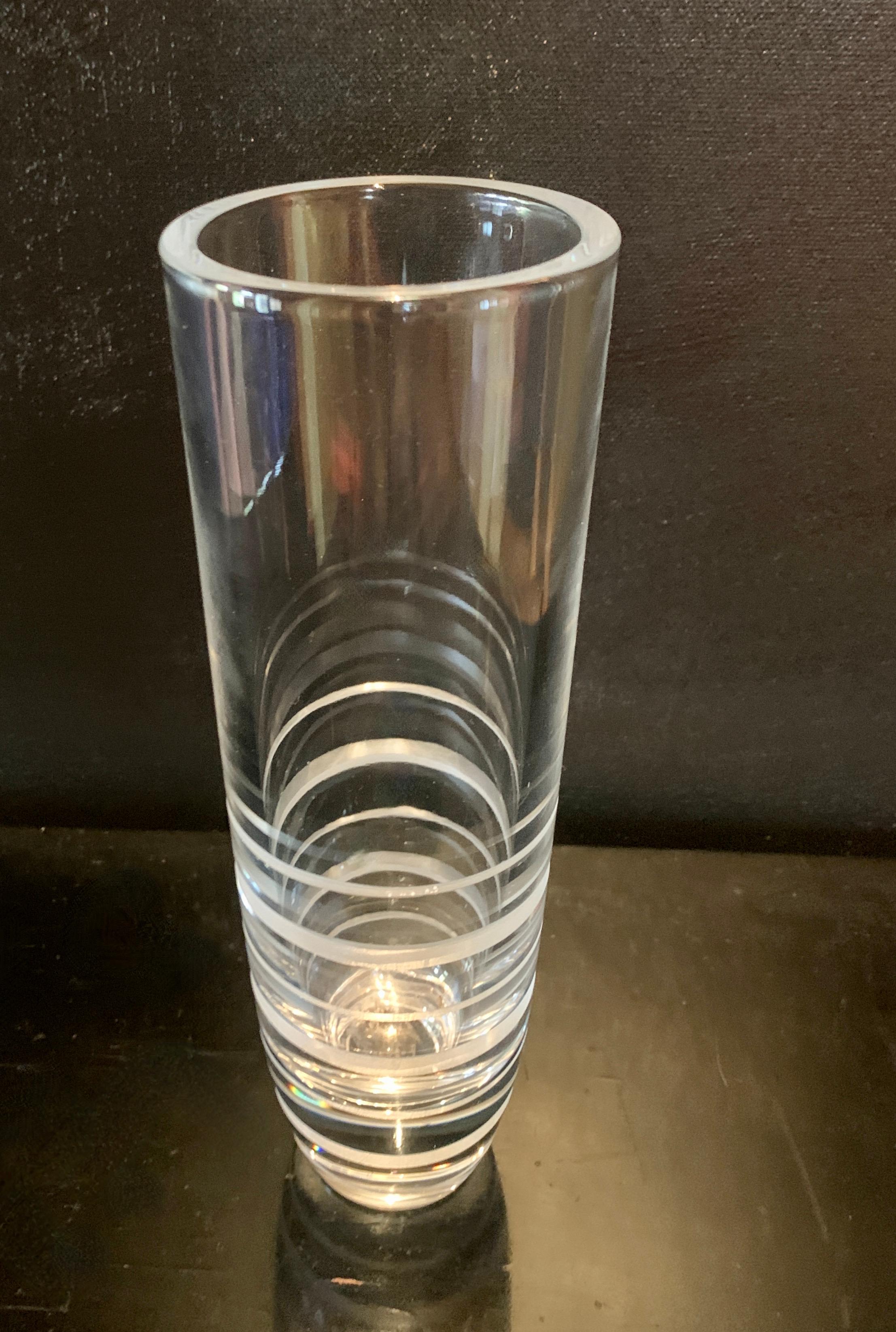 Un vase en cristal simple et moderne avec des cercles gravés à divers degrés vers la base. Bien qu'il s'agisse d'une pièce datant probablement du milieu du 20e siècle, le style se prête à un aspect propre et architectural, ce qui en fait un