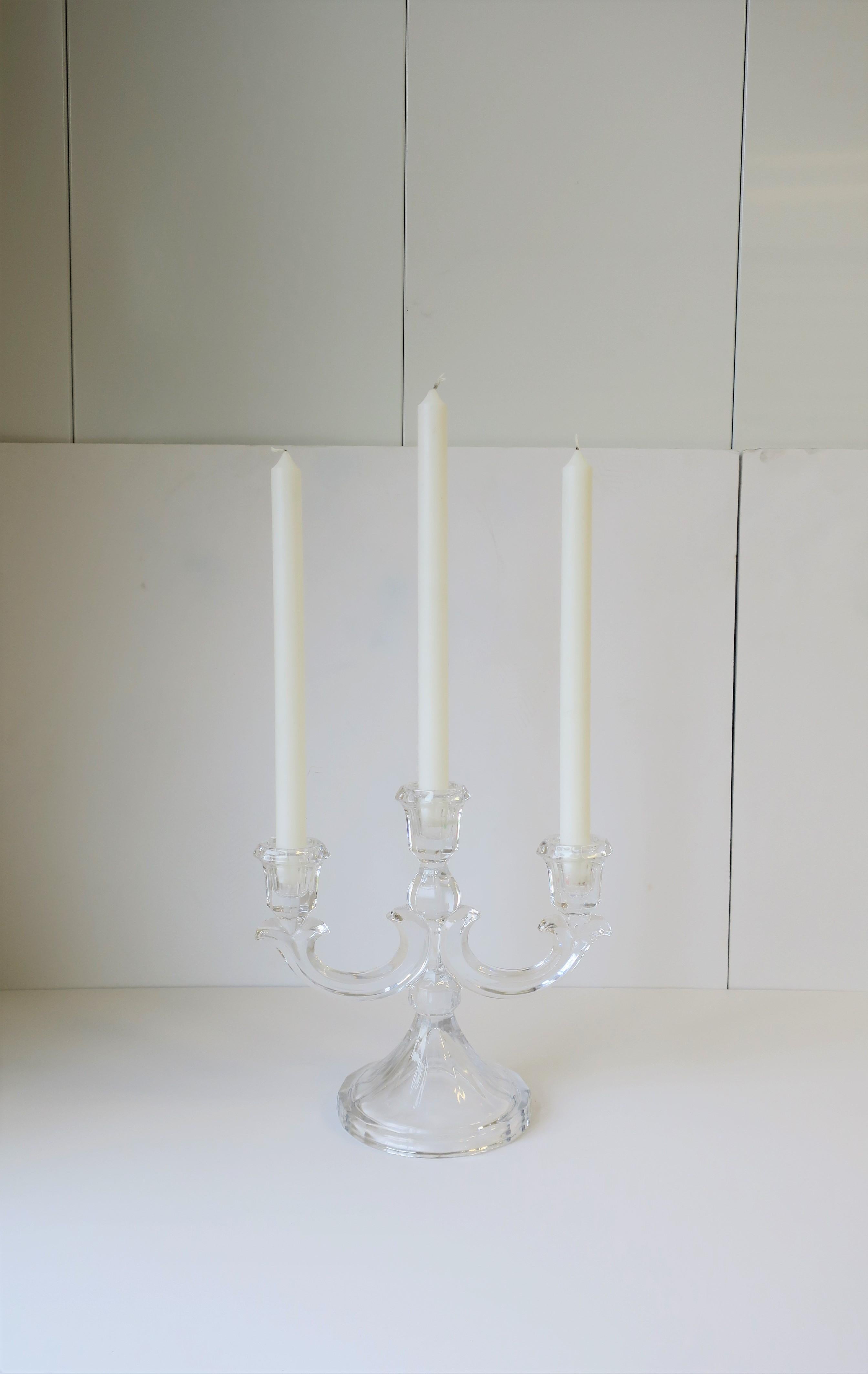 A beautiful and substantial crystal candelabra in the style of French luxury maker, Baccarat, circa 20th century. Candelabra holds three taper candles, as demonstrated. A candelabra is are a nice alternative to single candlestick holders. 

Piece