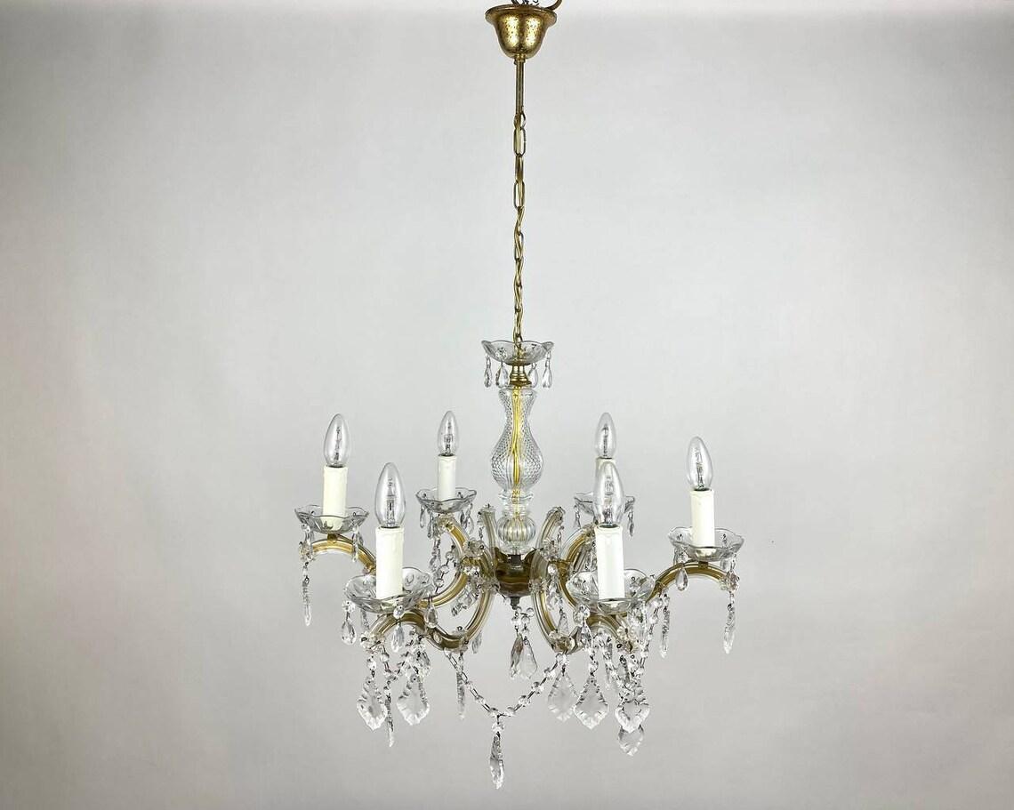 Chic crystal chandelier with gold metal frame, for 6 horns.

Richly Decorated with decorative elements and pendants made of transparent crystal chandelier.

There are no lampshades - the design of the lamps is made in the form of a candle in