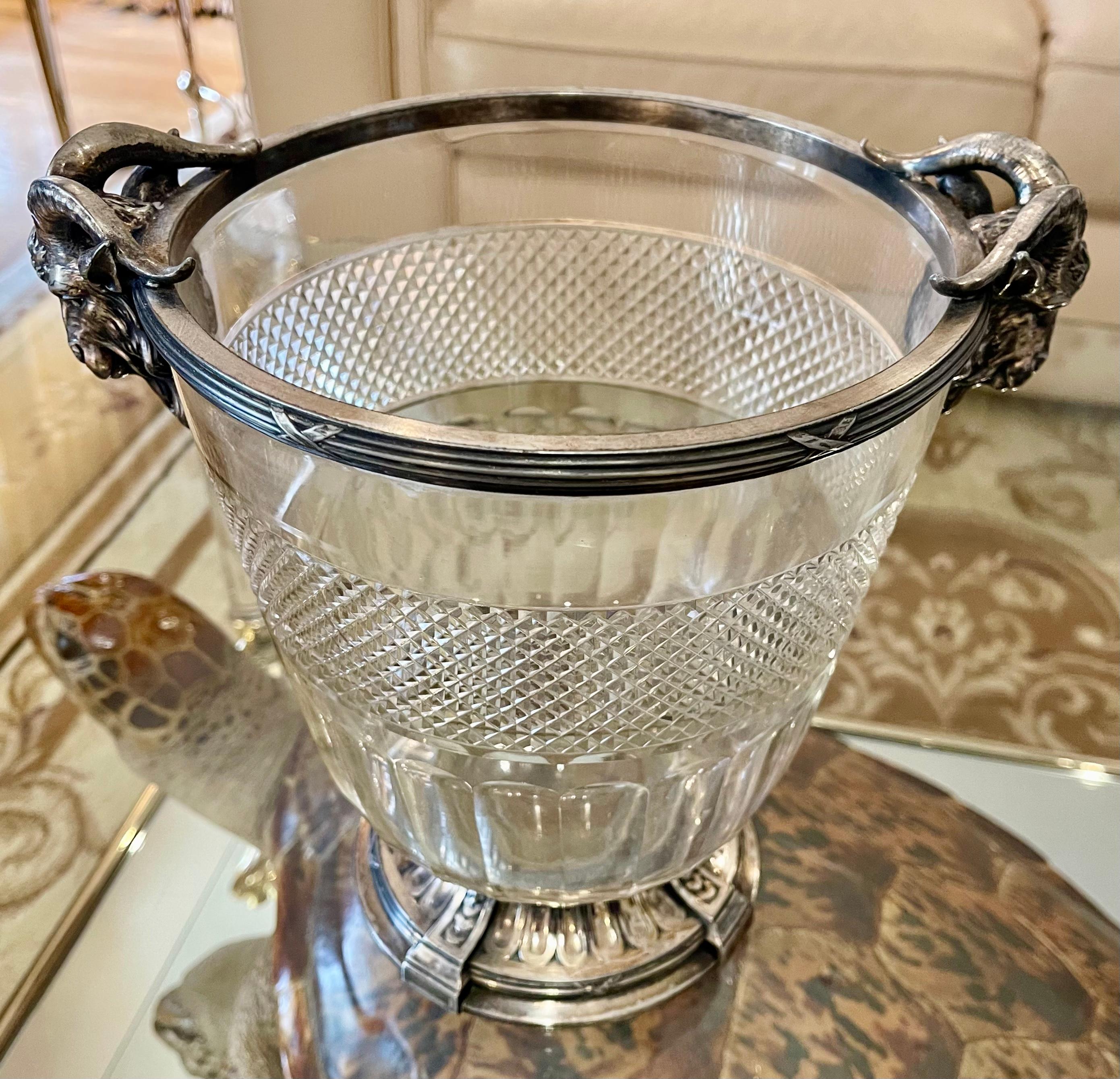 Crystal champagne bucket with silver metal frame. Two rams' heads are flanked on either side serving as handles. Very beautiful piece in good condition.

Dimensions
Height 25.5cm
Diameter 20.5cm