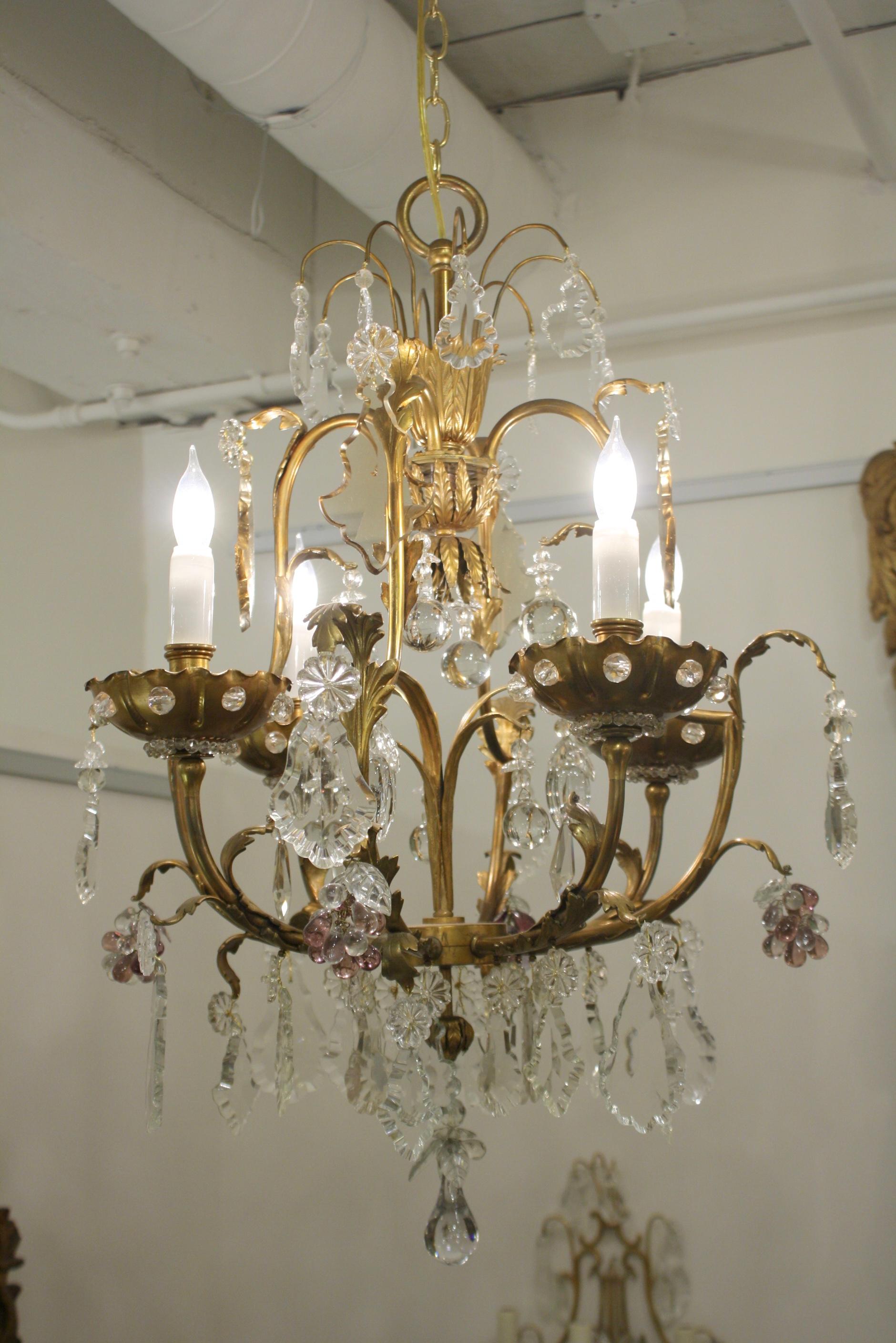 French bronze and crystal cage-form chandelier with four lights attributed to Maison Jansen. This chandelier is ornamented with a variety of different cut crystal pendalogues, grape clusters and pierced bobesches with crystal beads. The interior