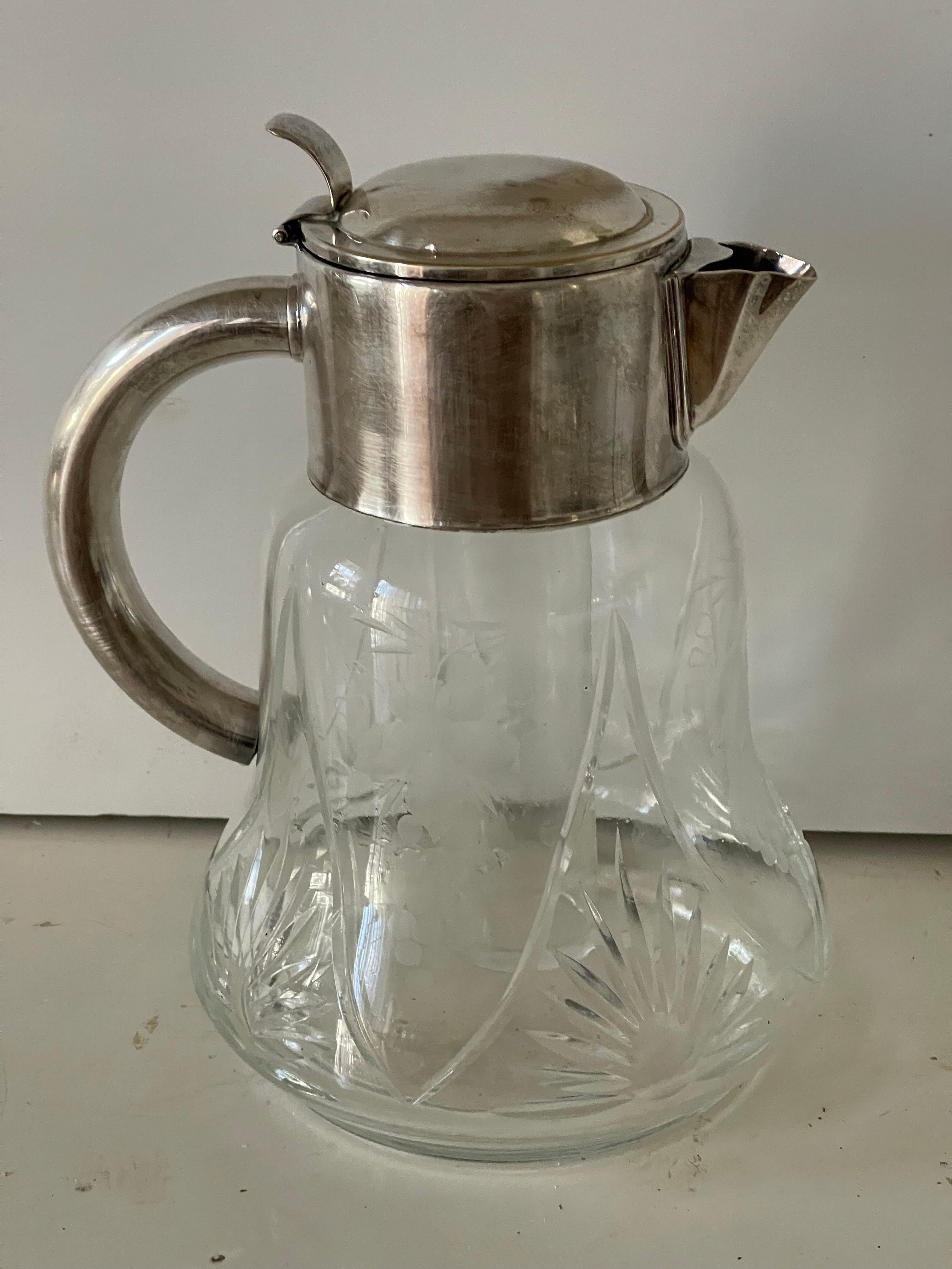 Jarra de agua vintage de cristal tallado con asa y tapa plateadas. 