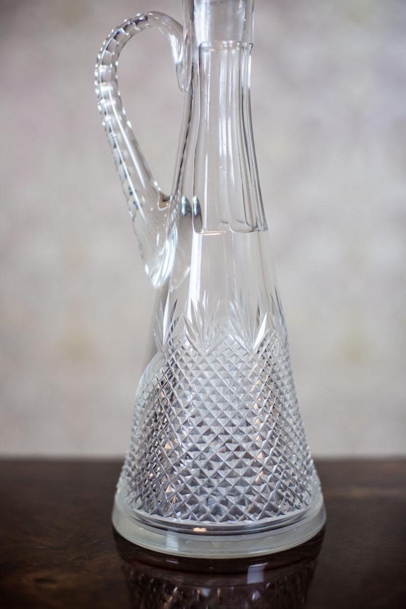 We present you a decanter in the shape of a slender pitcher.

The glass is crystal, handcut, and decorated with a unique pattern.

This item is in very good condition and undamaged.
