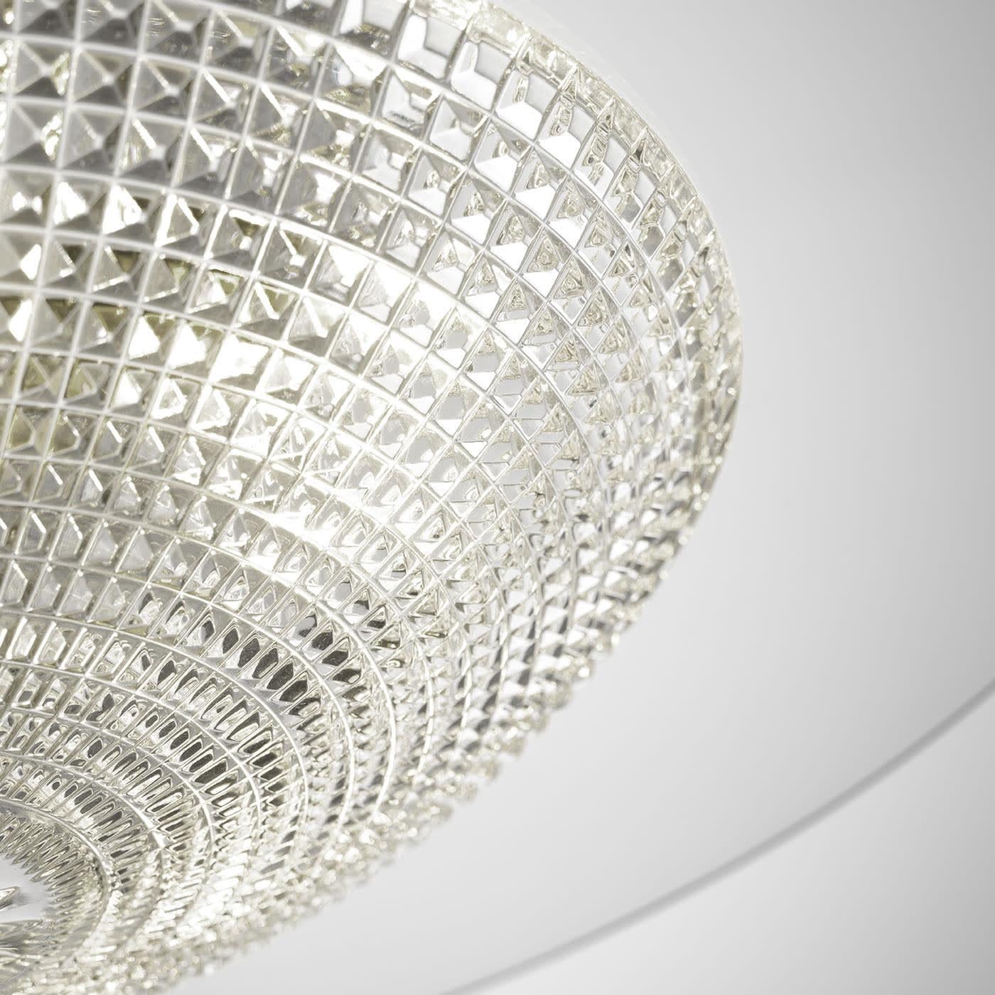 Exuding sophisticated and timeless charm, this chandelier is the masterful and daring synthesis between traditional and contemporary influences. The combination of prized crystal and glass - enhanced by the smooth circular panel topping the textured