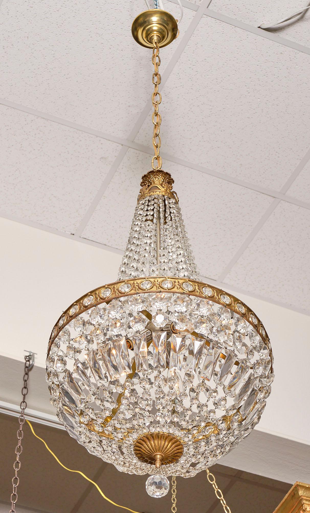 Crystal Empire style vintage chandelier from France with an embossed gilt brass structure and featuring an array of cut crystal. It has been newly wired to fit US standards.