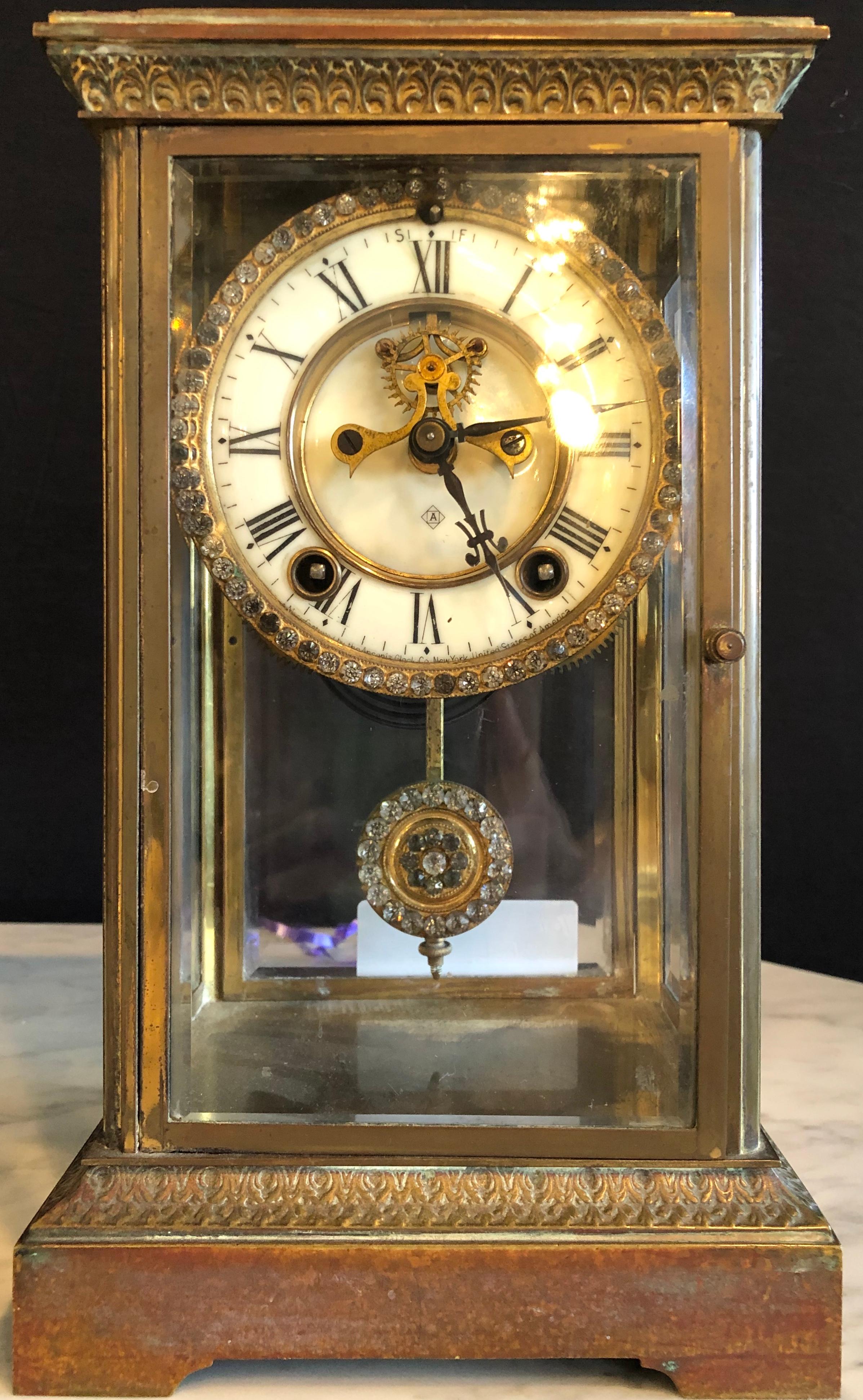 Reloj de esfera de cristal y péndulo fabricado por Ansonia Clock de Nueva York. Caja de bronce con marco de cristal biselado.