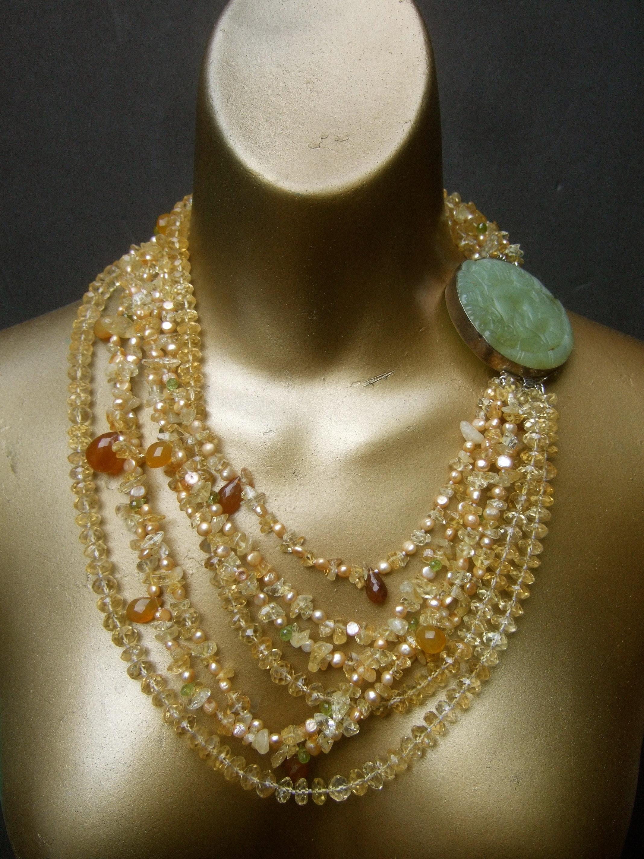 Crystal citrine glass beaded sterling silver carved jade medallion artisan necklace c 1980s 
The exquisite artisan statement necklace is comprised of seven rows of graduated strands of pale golden translucent yellow crystals. Juxtaposed with tiny